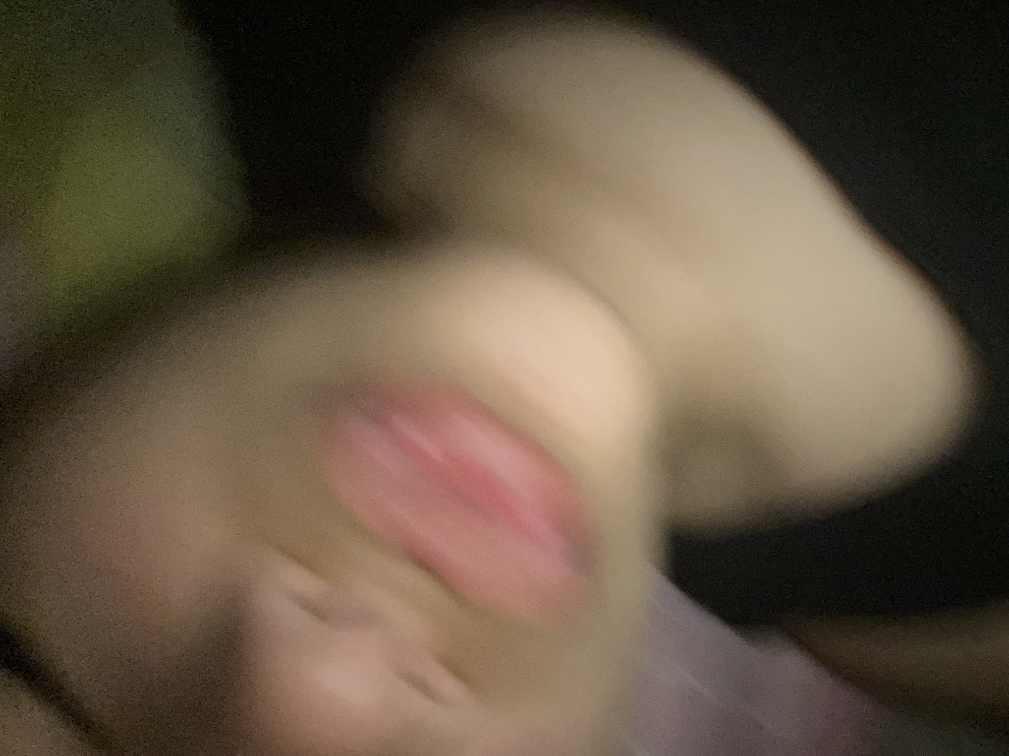 The image is blurry and indistinct. A human face with a partially visible mouth and tongue is visible. The overall color scheme is dark, and a dark area is in the background. Due to the blurriness of the image, further forensic detail is impossible. There are no visible indicators suggesting a location in Cotoperíz, Venezuela.