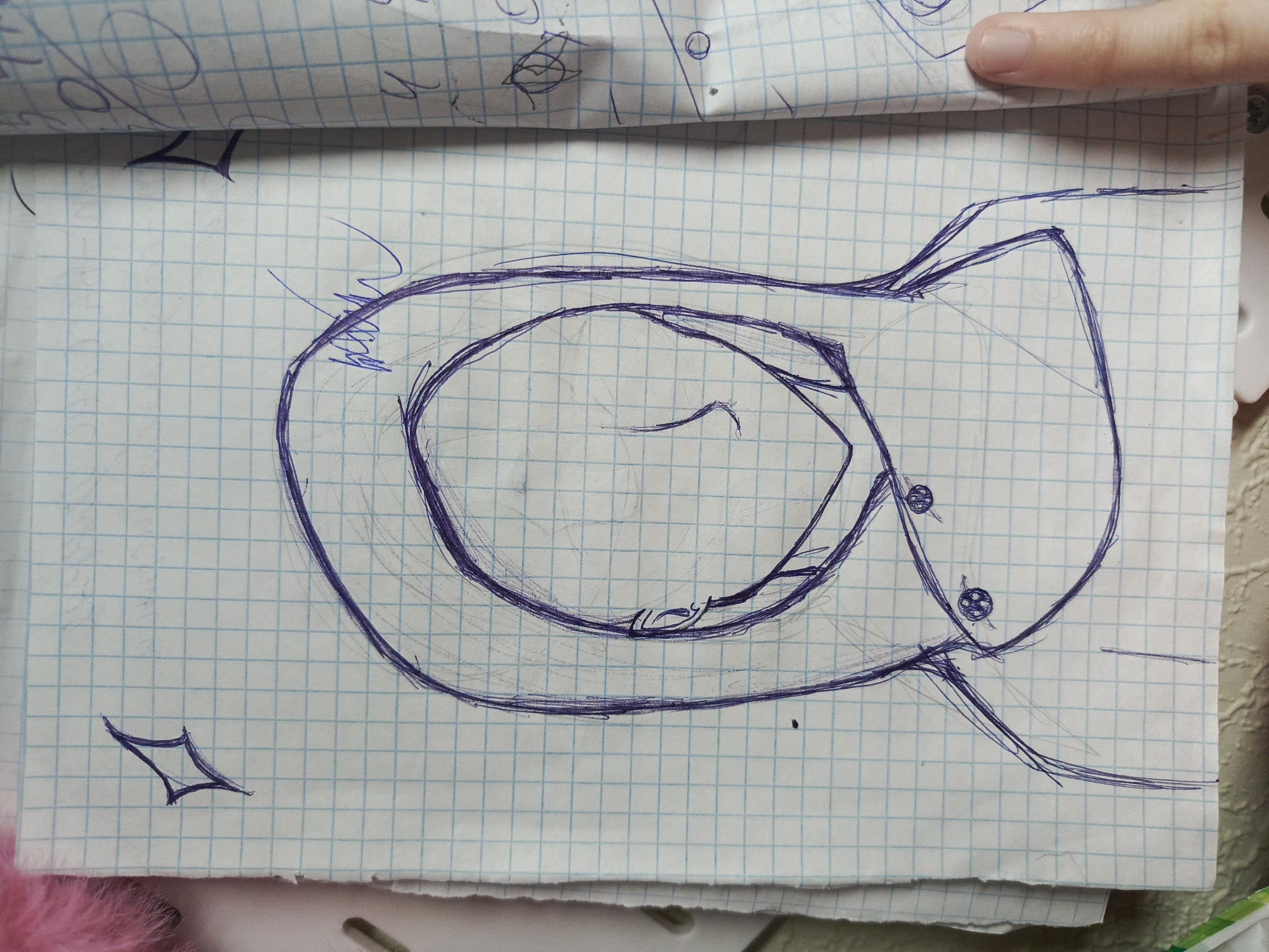 A sketch in blue ink on graph paper shows a cartoon-like elephant head facing right. The elephant has large eyes with detailed pupils and a curled trunk. Two additional sketches appear on the page: a diamond shape in the lower-left and a doodle near the top. The sketch appears to be located in Unknown, Unknown.