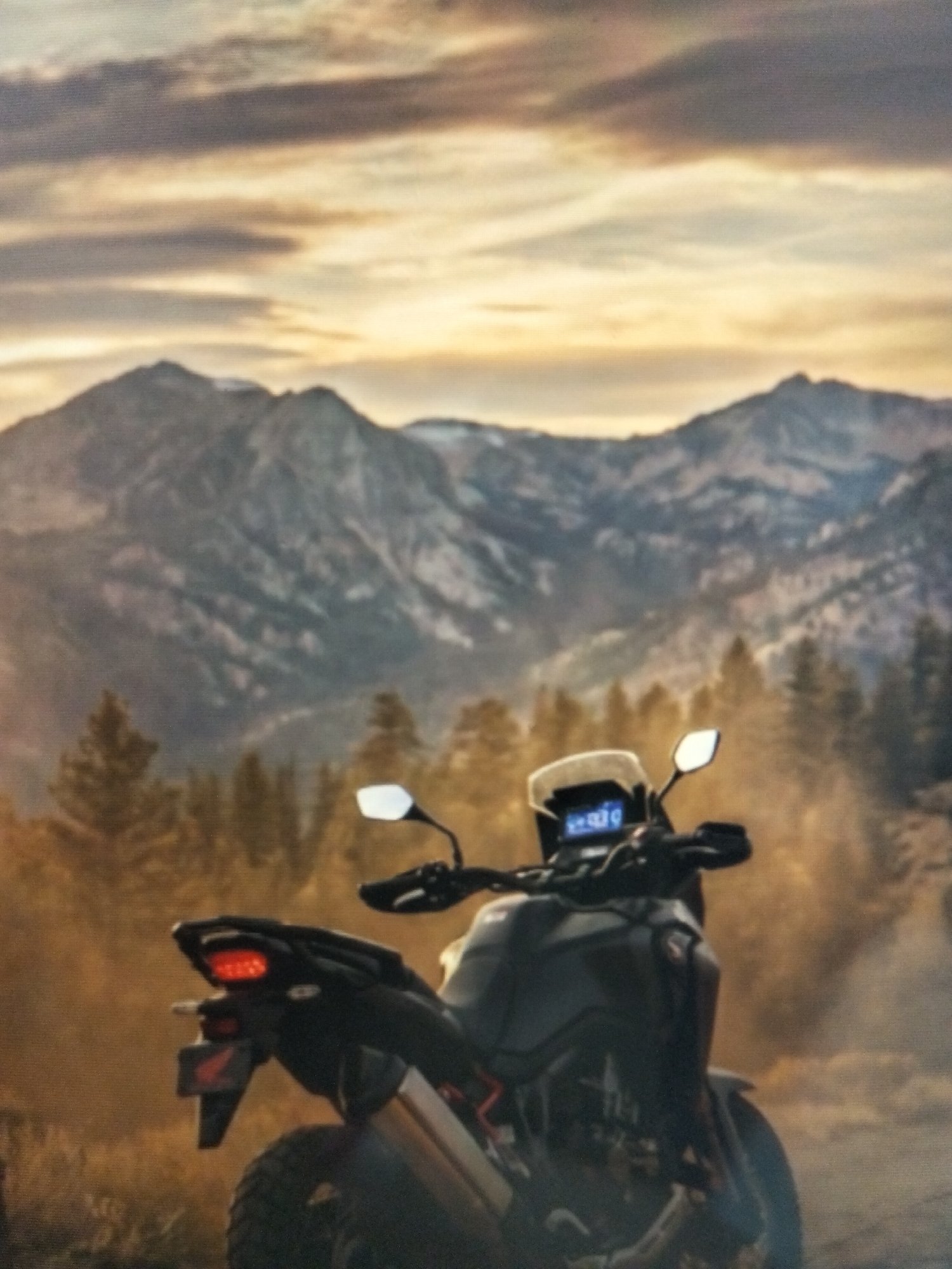 A black motorcycle with a white windscreen is parked in front of a mountainous landscape with pine trees and a dusty foreground. The sky is cloudy with hints of orange and yellow, suggesting either sunrise or sunset. The motorcycle's digital display shows some numbers. The rear brake light is illuminated red. A red Honda logo is visible on the rear fender. The image appears to be a digitally rendered illustration or a heavily filtered photograph. The location is specified as Payagaboh, Indonesia, though no specific urban features are visible in the image.