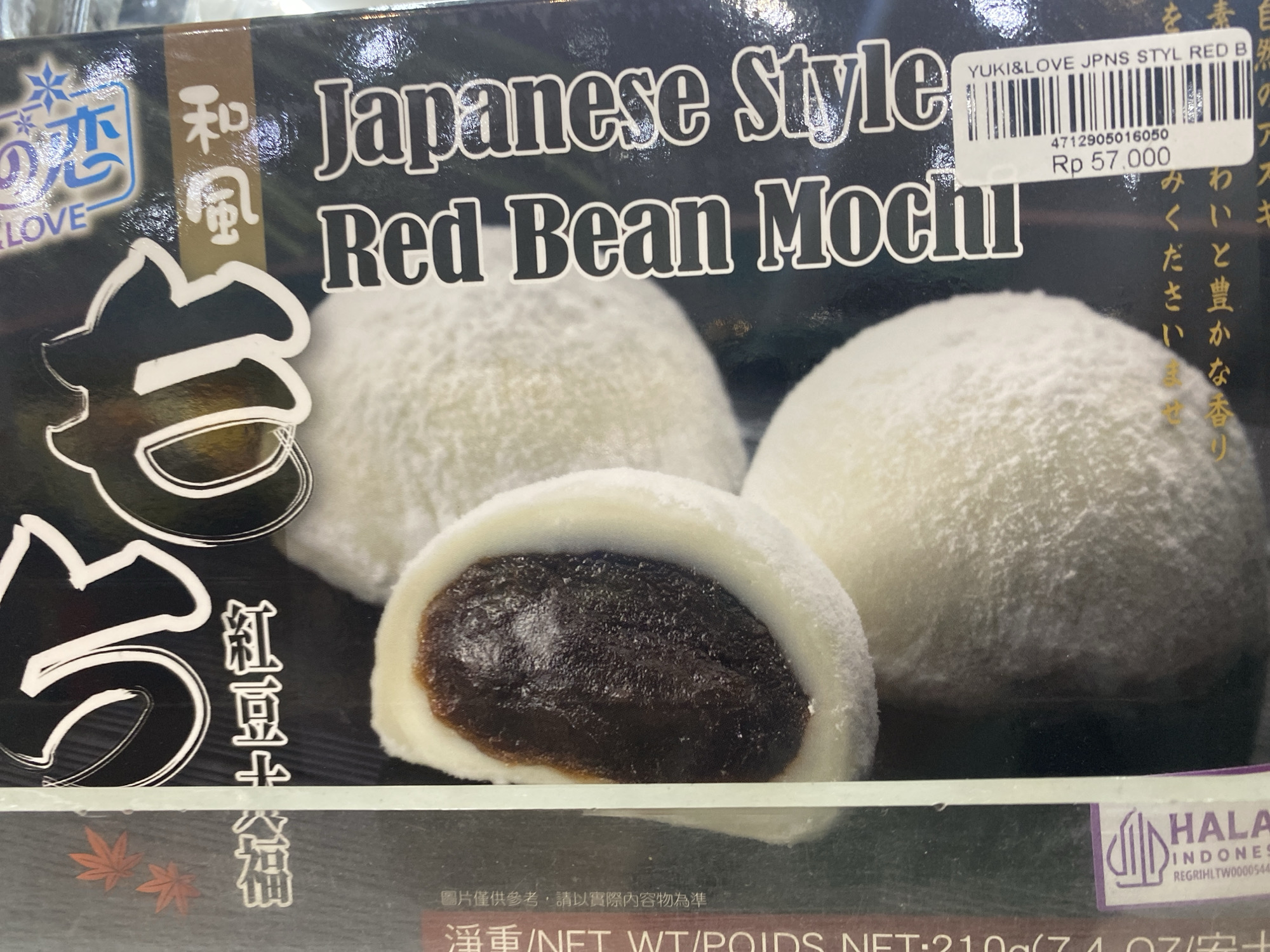 The image shows the packaging for "Japanese Style Red Bean Mochi" from the brand "Yuki & Love". The package features a picture of the mochi, with one cut open to reveal the red bean filling. The price tag shows "Rp 57.000", Indonesian Rupiah. There's a Halal Indonesian certification label, and the text "淨重/NET WT/POIDS NET:210g" indicating the net weight of the product is 210 grams. Based on the Indonesian Rupiah pricing and Halal certification, the image was likely taken in Indonesia, specifically the Kuta Selatan area based on the Halal certification details.