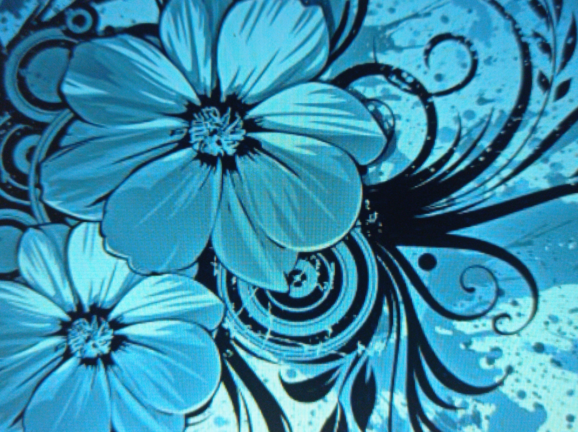 This image is a close-up photograph of a blue floral design with black tribal-like swirls and splatters. The design appears to be a digital illustration or graphic art, likely displayed on a screen, as indicated by the pixelation and moiré patterns visible throughout the image. There are no people, specific locations, or contextual elements that would allow for a description of a scene in the city of Mukachevo, Ukraine. The subject matter is purely abstract decorative art.