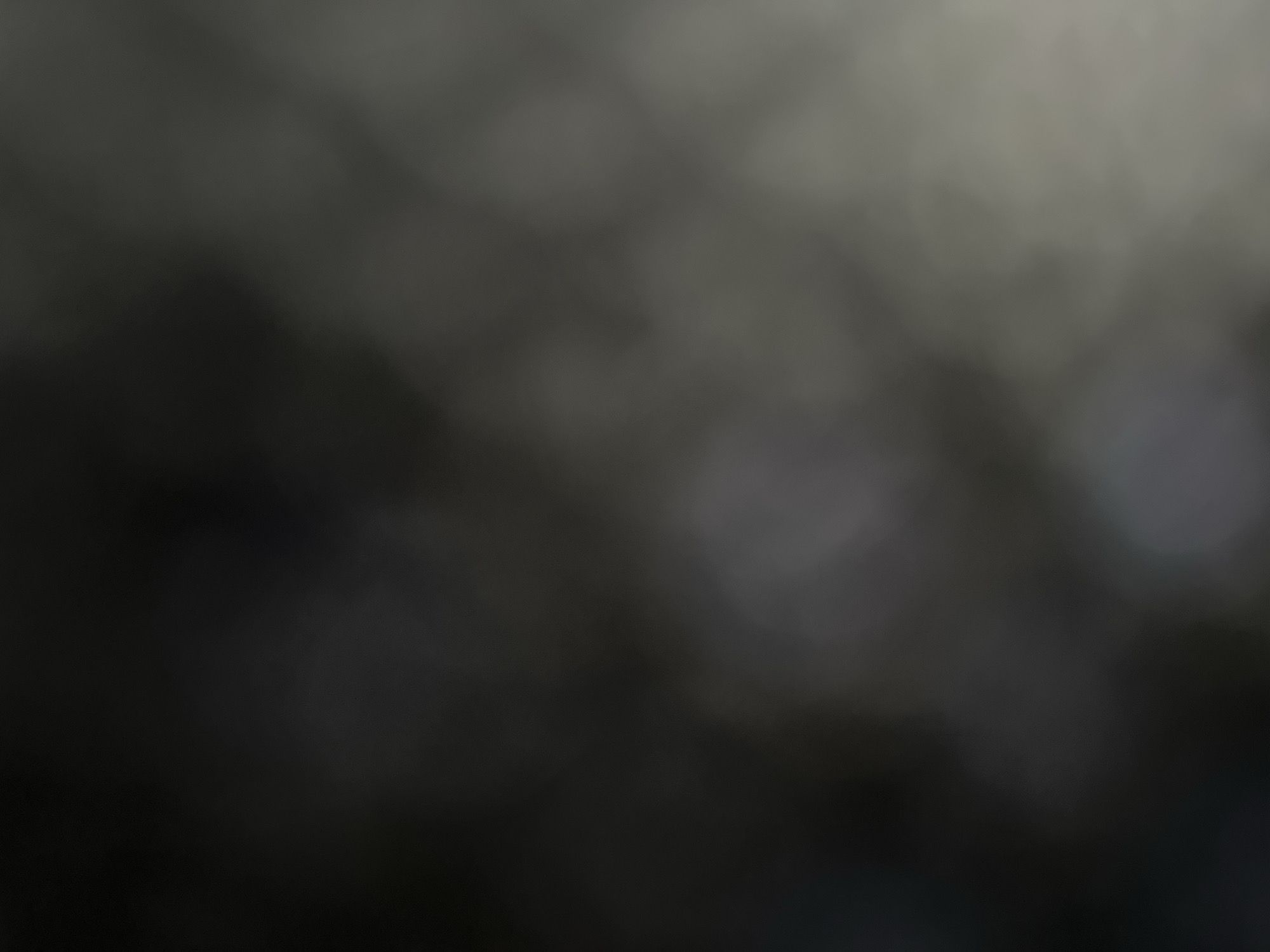 The image is a blurred, abstract photograph with a dark, monochromatic color palette. It displays soft, indistinct shapes and gradients, suggesting a low-light environment or a shallow depth of field. There are no discernible objects, people, or specific locations identifiable within the image. The overall impression is one of ambiguity and a lack of clear detail. The provided context of Belgrade, Serbia, cannot be visually verified from the image itself.