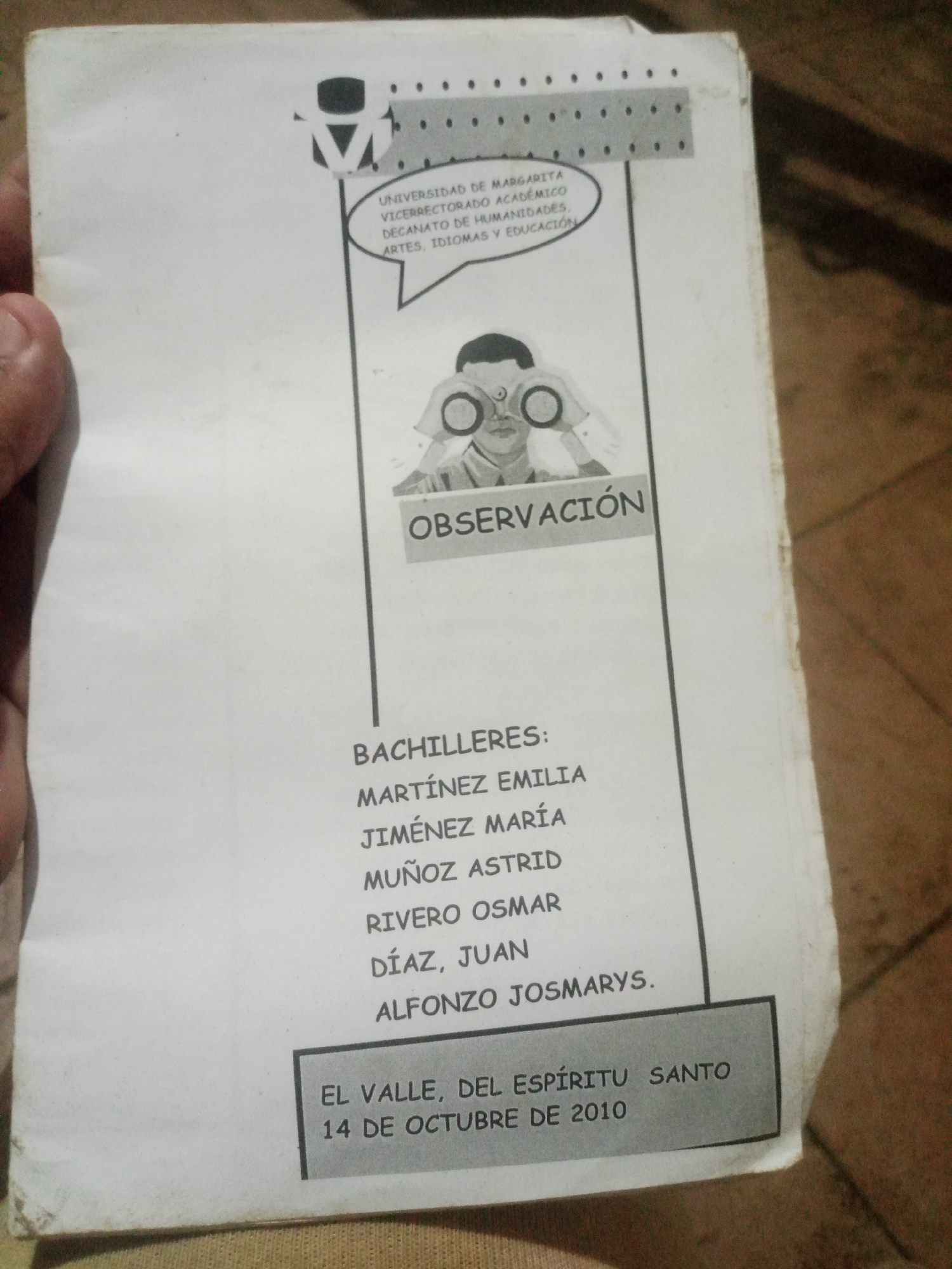 The image shows a close-up of a document, likely a school paper or report, with a title and a list of names. The document has a drawing of a person looking through binoculars. Text on the document includes "UNIVERSIDAD DE MARGARITA", "VICERRECTORADO ACADÉMICO", "DECANATO DE HUMANIDADES, ARTES, IDIOMAS Y EDUCACIÓN", and "OBSERVACIÓN". Below this, there is a list of names that appears to be a list of students: "BACHILLERES:", "MARTÍNEZ EMILIA", "JIMÉNEZ MARÍA", "MUÑOZ ASTRID", "RIVERO OSMAR", "DÍAZ, JUAN", and "ALFONZO JOSMARYS.". At the bottom, in a shaded box, is the text "EL VALLE, DEL ESPÍRITU SANTO 14 DE OCTUBRE DE 2010". There is no identifiable information in the image that places it specifically in Santa Ana, Venezuela. The background suggests the document is lying on a textured surface, possibly fabric.