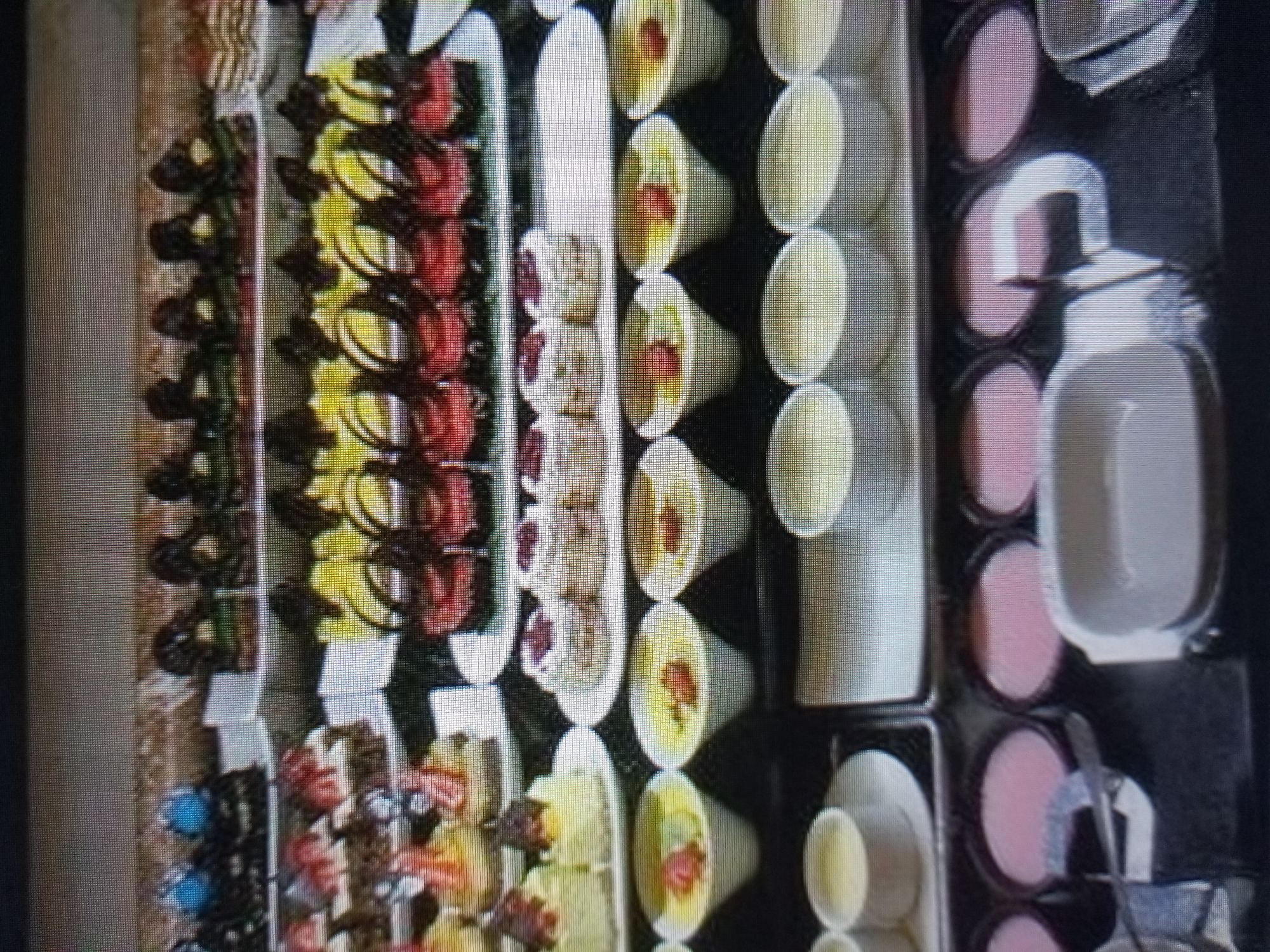 The image depicts a dessert buffet spread, likely in a hotel or restaurant setting. The buffet features a variety of colorful pastries, cakes, and individual dessert cups. In the foreground, several round white bowls contain a light yellow or cream-colored dessert, some topped with a single red fruit. Behind these, a rectangular white dish holds more of the same dessert. Further back, rows of small white cups also hold similar desserts.
The middle section of the buffet displays small cakes and pastries. On the left, there are several individual servings of cake, some topped with cream and fruit. To the right of these, a tray holds small, cylindrical pastries with white frosting and red berry toppings.
The top section of the buffet showcases a row of intricately decorated pastries. These appear to be small cakes or tarts with dark chocolate decorations and various colorful elements, including red and yellow frosting. To the left, there are also some darker pastries with blue toppings. The background is a blurred, neutral color, suggesting the focus is on the food display. There are no people visible in the image, and no clear indication of the specific location within Tiraspol, Moldova.