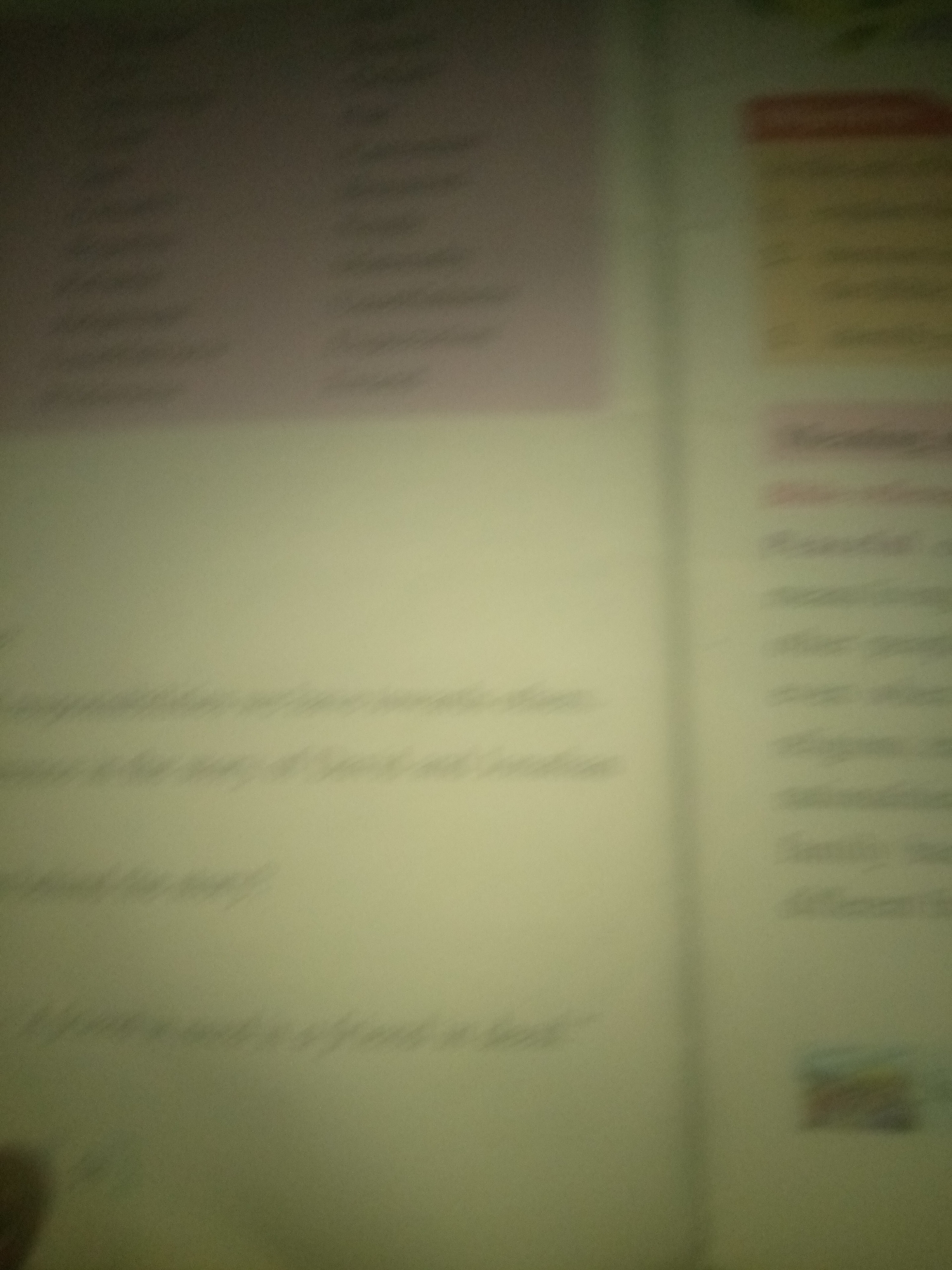 The image shows two pages of an open book, with text and some faint graphics. The left page has a large pink section at the top filled with what appears to be a list of words. Below this, there are several lines of blurred text, with some of it visible as "The story of" and "behind the story?". The right page has a yellow section at the top with some text, followed by more blurred lines of text. There are no discernible people or specific objects that can be identified with certainty due to the blurriness and low resolution of the image. The environment appears to be indoors, likely a room with artificial lighting. There is no information in the image that provides any context about the location in the city of Jauro Yinu, Nigeria.