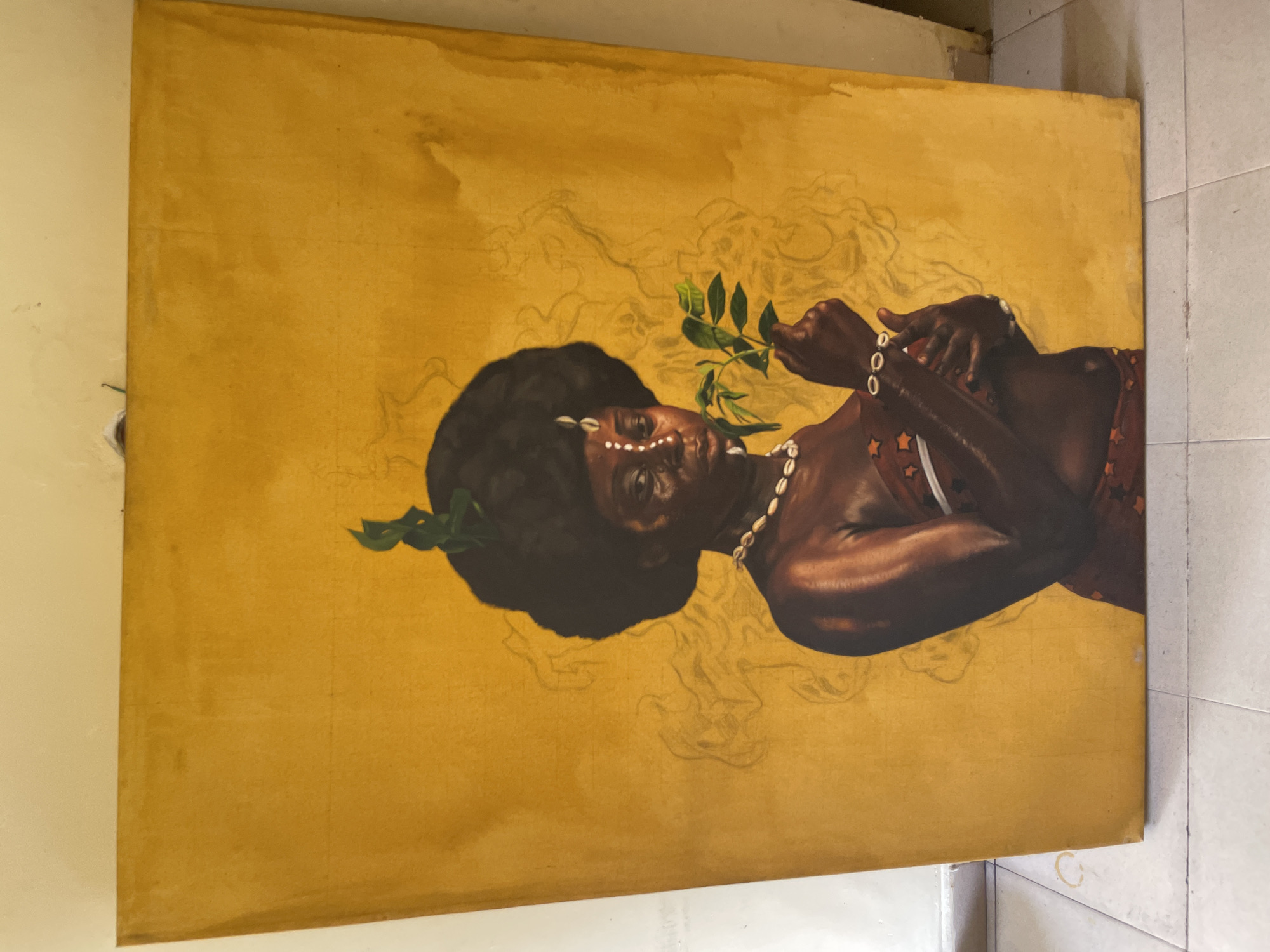 The media file displays a portrait painting of a dark-skinned woman, presented against a vibrant golden-ochre backdrop. The woman is depicted with a voluminous dark afro hairstyle, adorned with a green leafy branch tucked into the left side of her hair. Her face features distinctive white markings, possibly cowrie shells or painted dots, on her forehead and cheeks. She wears a necklace and bracelets made of cowrie shells, common cultural adornments. Her attire includes a reddish-brown garment with white star-like patterns visible on her shoulder.
The woman is captured holding a green leafy branch to her mouth and nose, appearing to be smelling or gently interacting with it, conveying a sense of contemplation or ritual. Her gaze is directed upwards and slightly to the right, suggesting introspection or a connection to a higher presence.
The background is dominated by warm golden-ochre tones, with faint, lighter-colored sketch lines visible throughout, indicating swirling patterns or an intentionally layered, possibly unfinished, state that adds an ethereal quality to the scene. The overall color palette is rich and earthy, emphasizing the natural elements and the woman's deep skin tones. The cultural elements, such as the cowrie shells and facial markings, align with traditions found in various African cultures, resonating with the provided context of Ado, Nigeria. There is no visible text in the image.