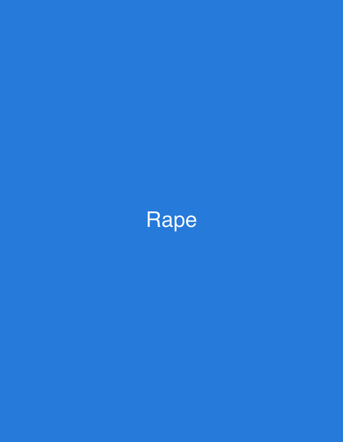 The image displays a uniform, solid blue background. Centered horizontally and vertically within this blue field is the single word "Rape," rendered in white, sans-serif typeface. No other elements, such as people, objects, additional text, or environmental features, are present. The background is entirely monochromatic, providing no visual information or context regarding a specific location. Therefore, the image's content does not visually present or imply a geographical location, including the city of New Stadium, Nigeria. The scene is exclusively textual against a plain colored backdrop.