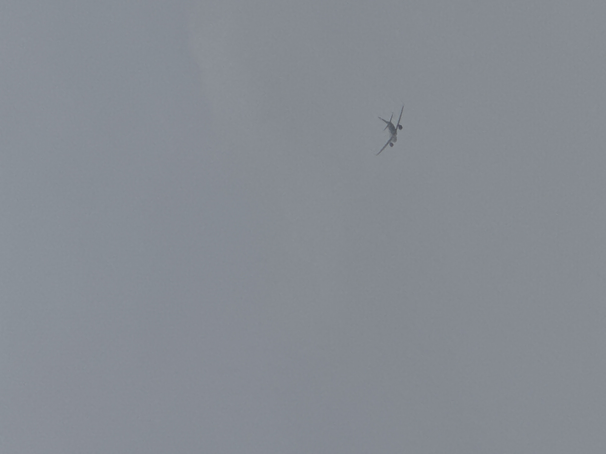 A distant commercial airplane is flying in a gray, overcast sky. The precise location within Yerevan, Armenia cannot be determined from the image.