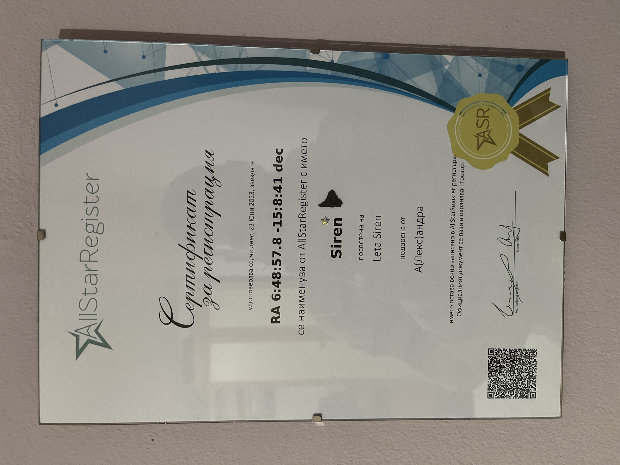 A framed "AllStarRegister" certificate hangs on a wall. The certificate is for the registration of the star "Siren". The certificate states the star is dedicated to Leta Siren and gifted by A(Лекс)андра on June 23, 2023. The certificate also contains a QR code. The certificate is in Bulgarian.