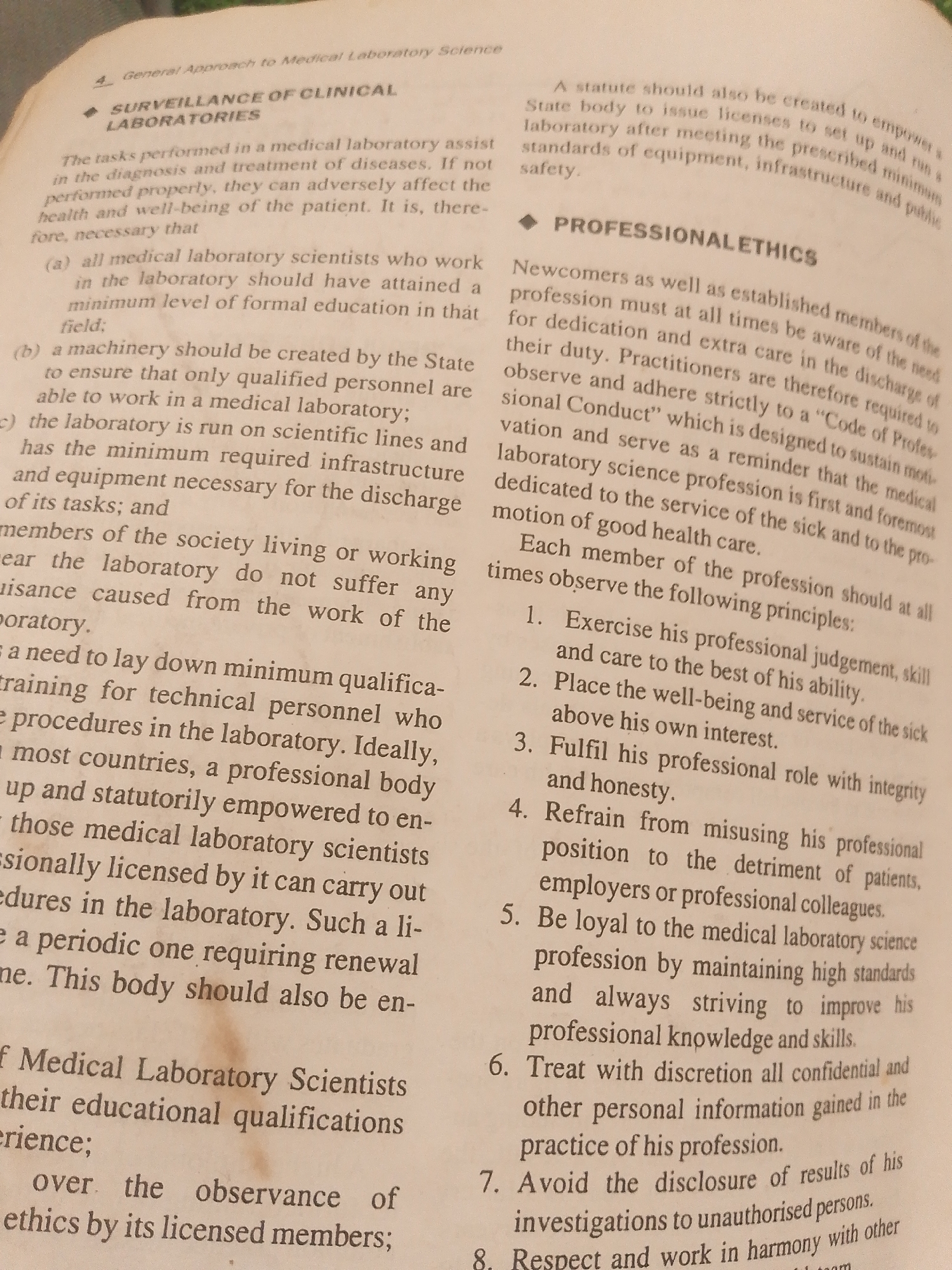 This is a close-up photograph of an open book, likely a textbook or manual related to medical laboratory science. The text is printed in black ink on off-white paper. The book is laid flat, with both pages of a spread visible. The lighting suggests an indoor setting, possibly a room with artificial light as there are no strong shadows or indications of natural light sources.
The content of the book focuses on aspects of medical laboratory science, specifically detailing the "SURVEILLANCE OF CLINICAL LABORATORIES" and "PROFESSIONAL ETHICS." It outlines the responsibilities of laboratory scientists, the need for qualifications and infrastructure, and a code of conduct. Bullet points and numbered lists detail principles of professional practice, such as exercising judgment, prioritizing patient well-being, and maintaining integrity and confidentiality.
There are no people, objects other than the book itself, or distinct elements of a scene or setting visible in the image. The focus is entirely on the printed text. The "Location context: Jalingo, Nigeria" provided is not inferable from the visual information in the image. The notable details are the subject matter of the text and the clarity of the printed words. The text is the primary and only notable detail.