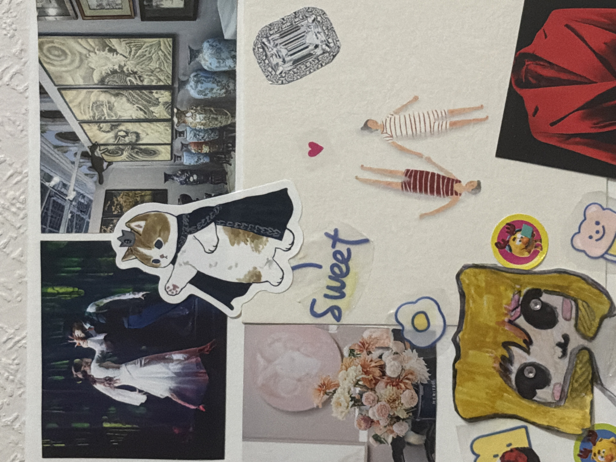 The image displays a collage of various cutouts and photographs pasted onto a textured white surface, resembling a wall or a large piece of paper. The collage is comprised of diverse elements including a photograph of two dancers in a dark, stage-like setting with green foliage in the background. Adjacent to this is a photograph of an indoor art exhibition featuring several large framed artworks with oriental motifs, displayed alongside a collection of decorative vases. A sticker of a cat wearing a crown and a dark cape is prominently placed in the center, partially obscuring the two photographs.
Below these, to the left, is a photograph of a bouquet of pink and orange flowers in a dark vase, with a circular pastel pink cutout behind it. To the right of the flowers, the word "Sweet" is written in blue marker on a yellow translucent background. Further down and to the right, there are two miniature figures of people in striped outfits. Above these figures is a sparkling diamond ring cutout. Below the figures, a red blazer is depicted on a black background.
Scattered throughout the collage are other smaller cutouts, including a cartoonish drawing of a person with yellow hair and large eyes, some circular stickers with cartoon characters, and a small pink heart shape. The overall impression is a personal collection of images and decorative elements. There is no discernible location in the city of Moscow, Russia, indicated in the image.