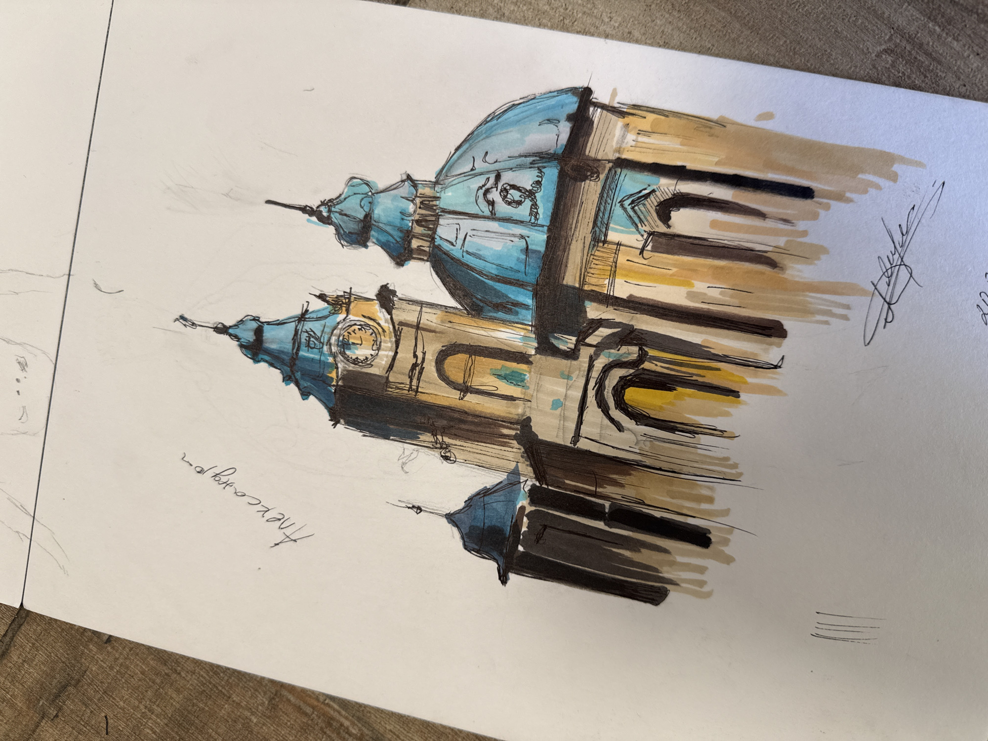 A sketch depicts St. Nicholas Russian Church in Sofia, Bulgaria, with two blue-domed towers visible. The architectural style is rendered with black outlining and shading, complemented by brown and yellow strokes to indicate light and shadow. A clock face is visible on the lower tower. The sketch is on white paper, placed on a wooden surface, with the signature of the artist present.