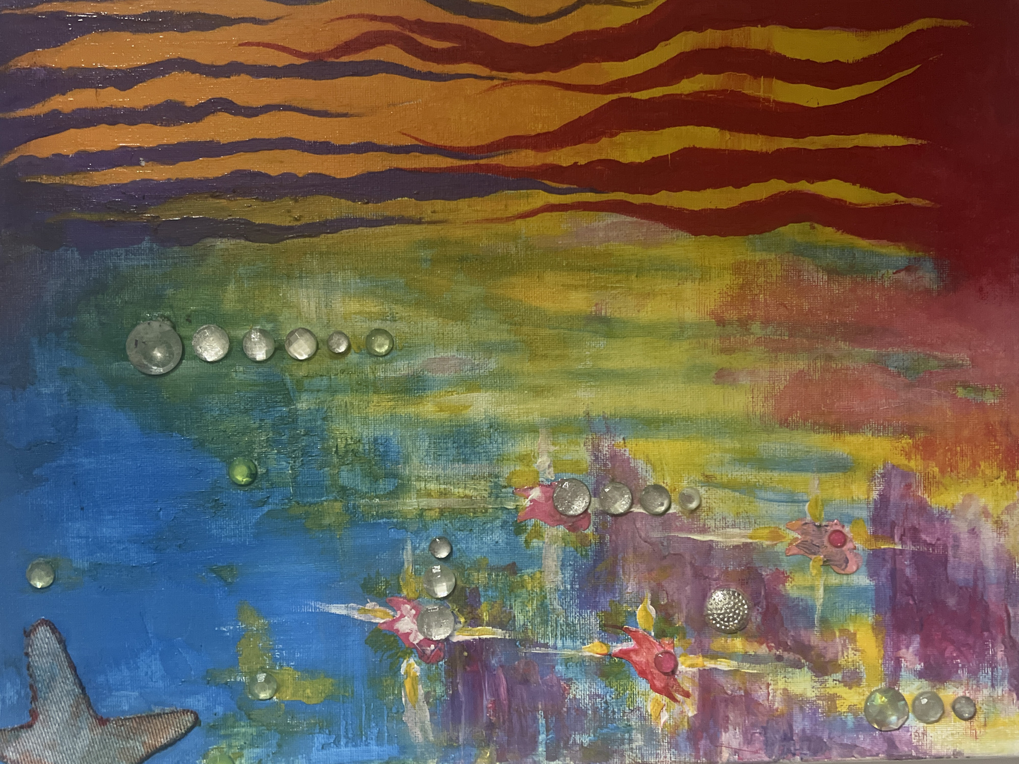 This is an abstract painting with a vibrant and textured surface. The left side of the painting features a rough, blue background with hints of yellow and green. A stylized, light-colored starfish with a denim-like texture is positioned in the upper left corner. Scattered across this section are small, clear, spherical embellishments that resemble dew drops or small bubbles, along with a few green circular dots.
The central portion of the painting transitions into a blend of yellow, green, and reddish-purple hues, creating a watery or abstract floral effect. Within this area, there are several small, pink abstract shapes that could be interpreted as stylized fish or flowers, each accented with a circular, metallic embellishment. More of the clear spherical embellishments are present, arranged in a vertical line down the center.
The right side of the painting is dominated by vertical, flame-like shapes in shades of orange, red, and purple. These shapes appear to be painted with thick, textured strokes. The overall impression is one of contrasting elements, possibly representing a combination of marine life and fire or a vibrant, chaotic underwater scene.
There is no information available to determine if this painting is located in Sofia, Bulgaria, or any other specific location.