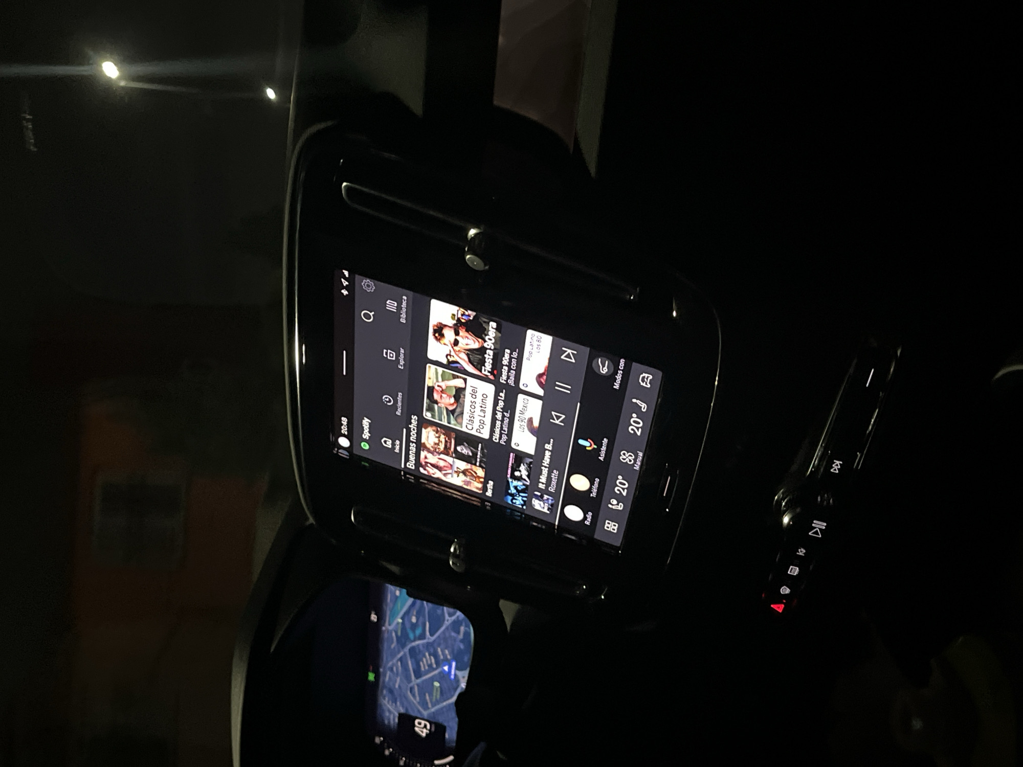The image depicts the interior of a car at night. The car's infotainment system is prominently displayed, showing the Spotify application with a playlist featuring pop music. The screen also shows the temperature set to 20°C. A map application is visible in the lower part of the image. The image does not provide sufficient details to determine the location in San Bernardino Tlaxcalancingo, Mexico.