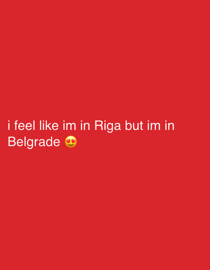 The image is a red background with white text that reads "i feel like im in Riga but im in Belgrade" with an emoji of a face with heart eyes at the end.