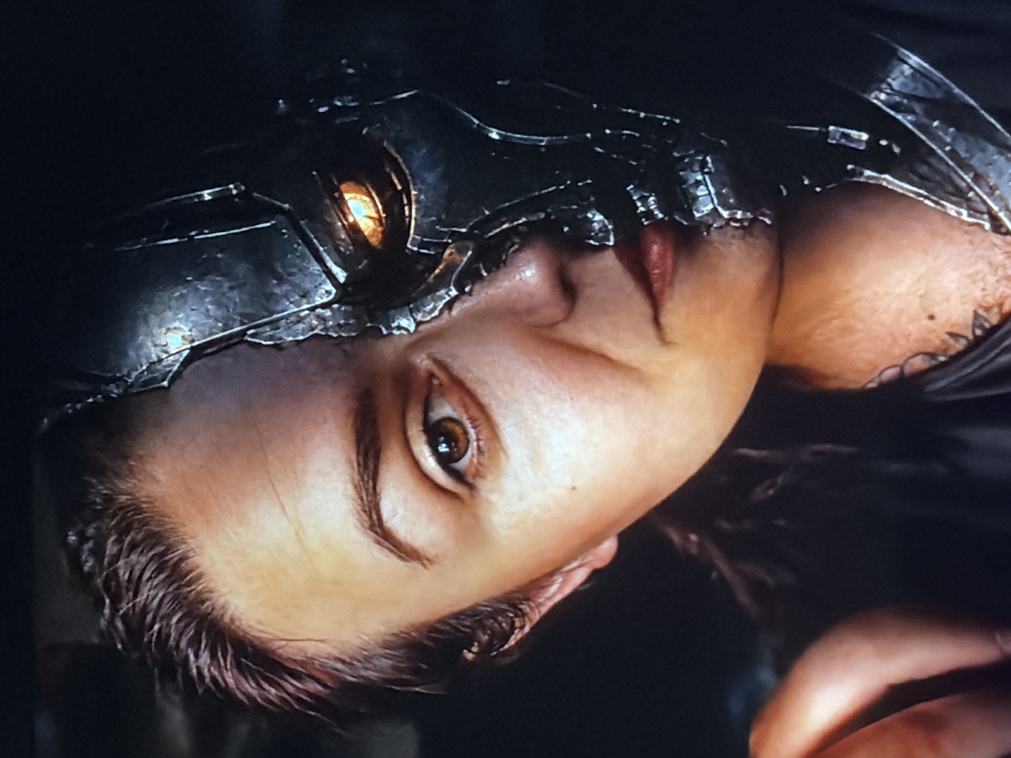 The image is a close-up of a person's face, split in half. One side of the face appears to be human, with an eye and part of the nose and mouth visible. The other side of the face is a metallic, robotic structure, with a glowing orange eye. The background is dark and out of focus. There is no identifiable location within the city of Chișinău, Moldova.