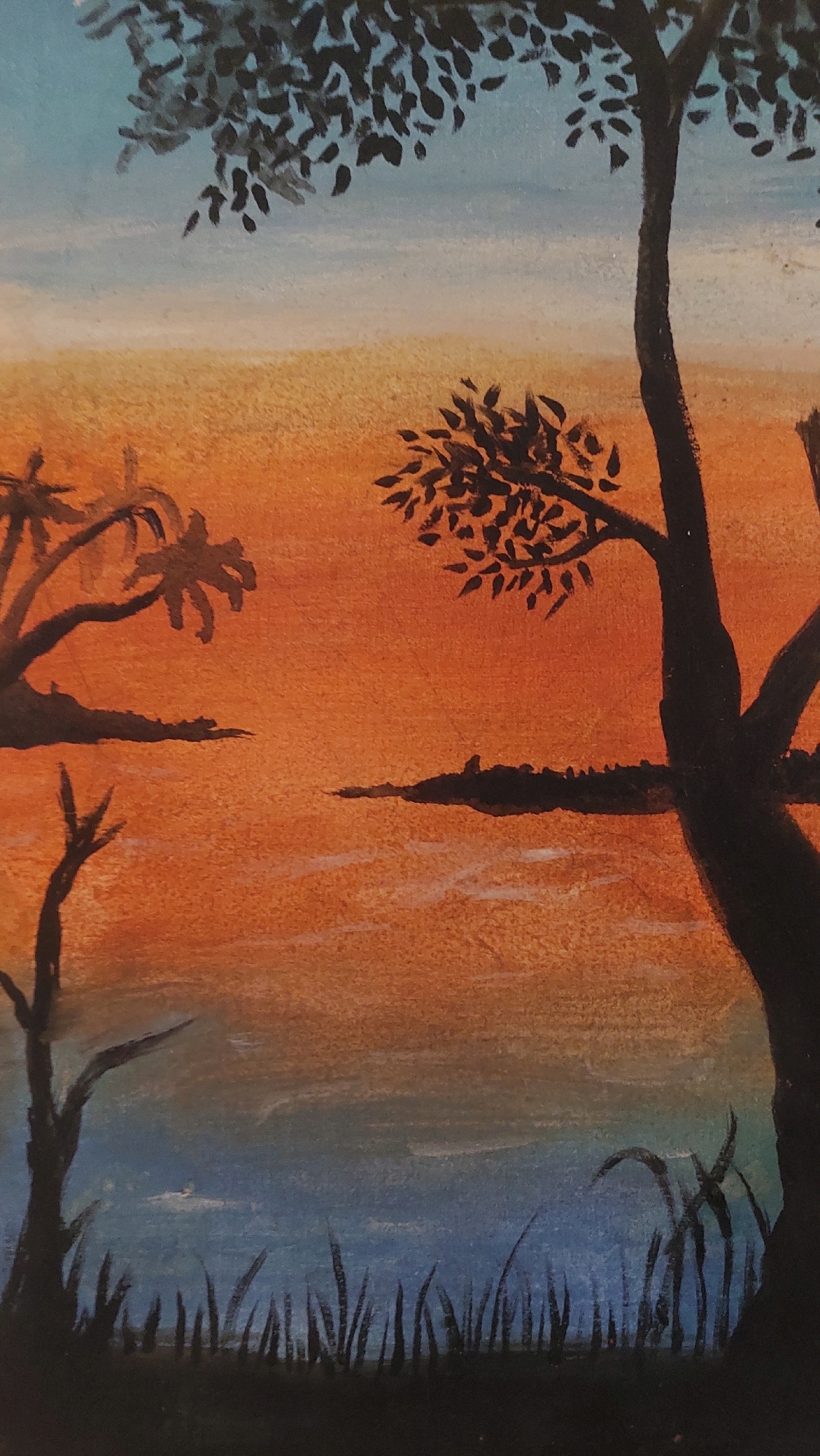 The image is a painting of a sunset over a body of water, likely a river or lake, with silhouetted trees and vegetation. The sky transitions from a pale blue at the top to a vibrant orange and then a lighter hue near the horizon. In the foreground, dark green and black reeds or grass are depicted against a dark silhouette at the bottom. Two silhouetted trees with dense foliage are prominent in the mid-ground and right side of the image. On the left, a silhouetted palm tree with sparse fronds is visible, along with a thin, leafless silhouette of a tree. A dark, elongated landmass or island with a textured surface is present in the middle distance, with faint white lines suggesting ripples or waves on the water. The overall impression is a tranquil, tropical landscape at dusk. There is no indication of the city of Bojong Gede, Indonesia, within the image itself.