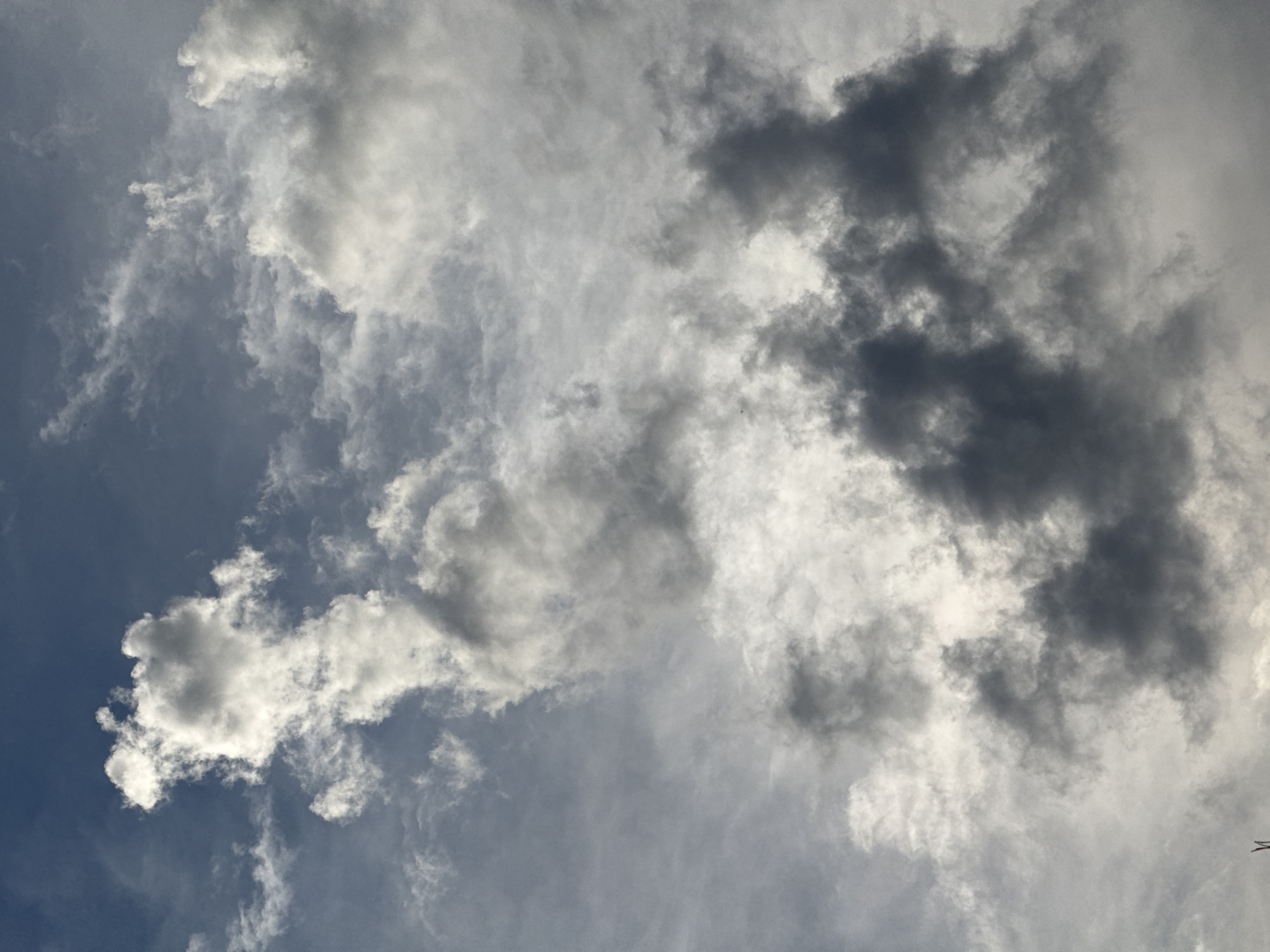 A cloudy sky is shown in the image. The clouds are various shades of gray and white, with some patches of blue sky visible in the upper portion of the image. The clouds are dense and appear to be moving, suggesting a dynamic weather system. The image does not depict any people, subjects, or objects, and no actions or interactions are occurring. The environment is solely the sky. There is no information in the image to suggest its location in Mikhaylovsk, Russia, or any other specific city.