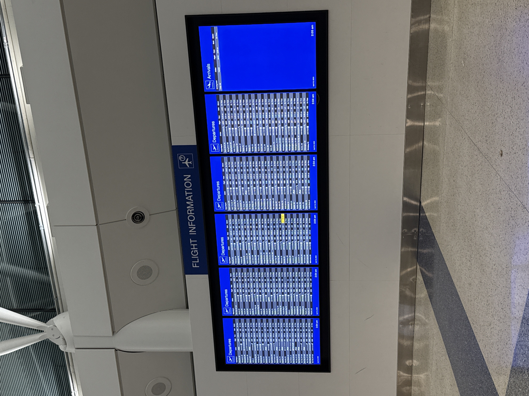 This image shows a flight information display board at an airport. The board displays arrivals and departures. The time is approximately 2:00 AM and the date is April 10, 2020. The airport is likely located in Chicago, United States of America. The photo is taken indoors.