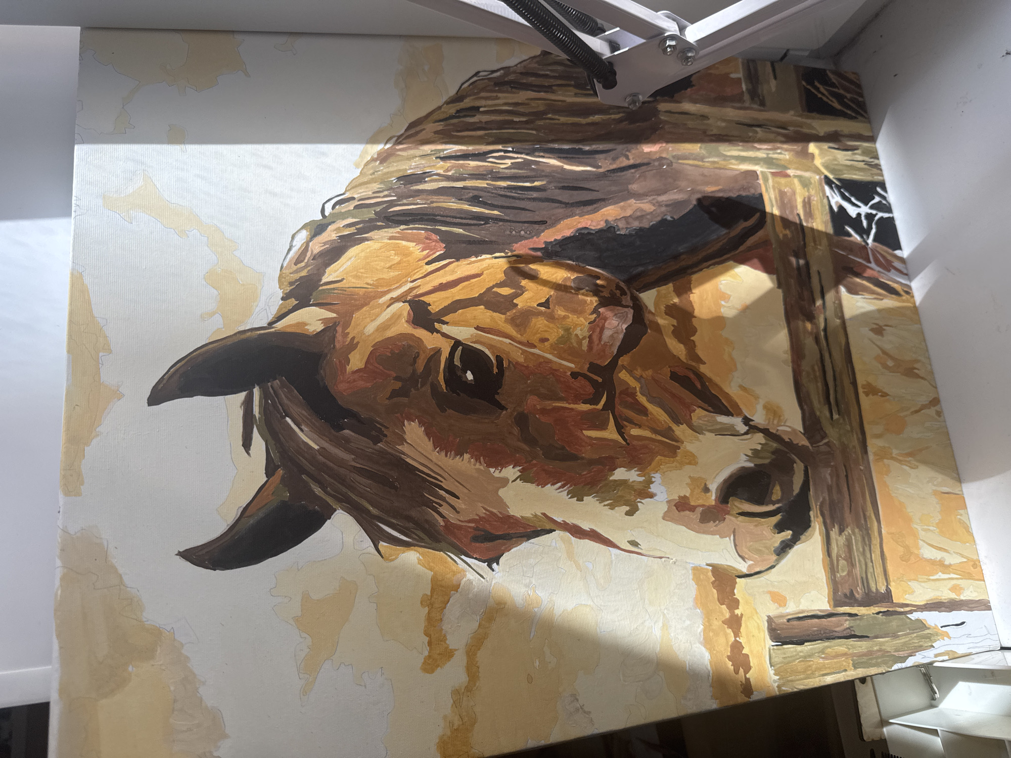 The image shows an unfinished painting of a horse's head. The horse is depicted in a profile view, facing left. The painting is rendered in a loose, impressionistic style with broad brushstrokes. The horse's coat is a warm brown, with lighter areas on its face and neck. Its mane is a darker brown and appears windswept. The background is a pale yellow, with suggestions of clouds or a hazy sky. In the foreground, there is a wooden fence.
The painting is on a canvas and is propped up, suggesting it is in the process of being created. A light fixture with a metal arm is visible on the right side of the image, possibly used for lighting the workspace.
The image does not contain any identifiable landmarks or elements that would allow for its location to be determined in the city of Perm, Russia. The scene appears to be an indoor art studio or a similar creative space.