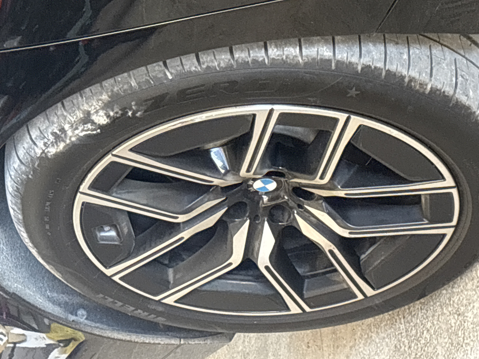 The image shows a close-up of a car tire. The tire is a Pirelli P Zero. The wheel is a BMW wheel, with a black and silver design. The car appears to be black. The image does not contain enough information to determine a location in Asenovgrad, Bulgaria. The image includes an object: a car tire with its wheel. There are no people present.