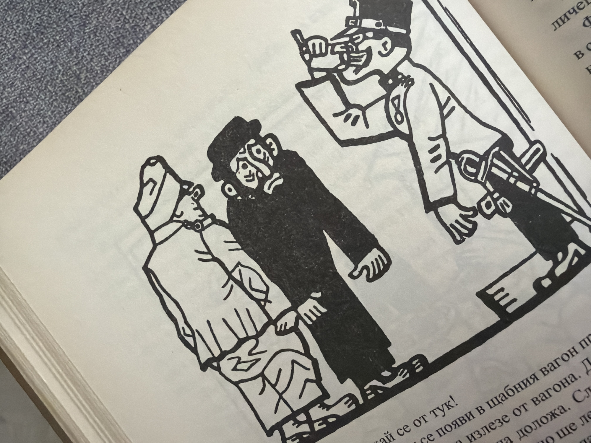 The image is an illustration featuring three figures in a stylized, black and white artistic rendering. The figures appear to be men, depicted with simple lines and heavy shading. The first figure, on the left, is wearing a uniform with a cap and seems to be walking or standing. The second figure, in the center, is dressed in darker clothing and a hat, with a distinct facial expression. The third figure, on the right, is also in uniform, holding a pistol. There is text in Cyrillic script visible in the lower left corner of the image. The illustration is presented on a page within a book, with some of the book's binding and textured surface visible. The overall style suggests it could be from a children's book or a historical publication. There is no discernible location in the city of Pazardzhik, Bulgaria, depicted or indicated within the image.