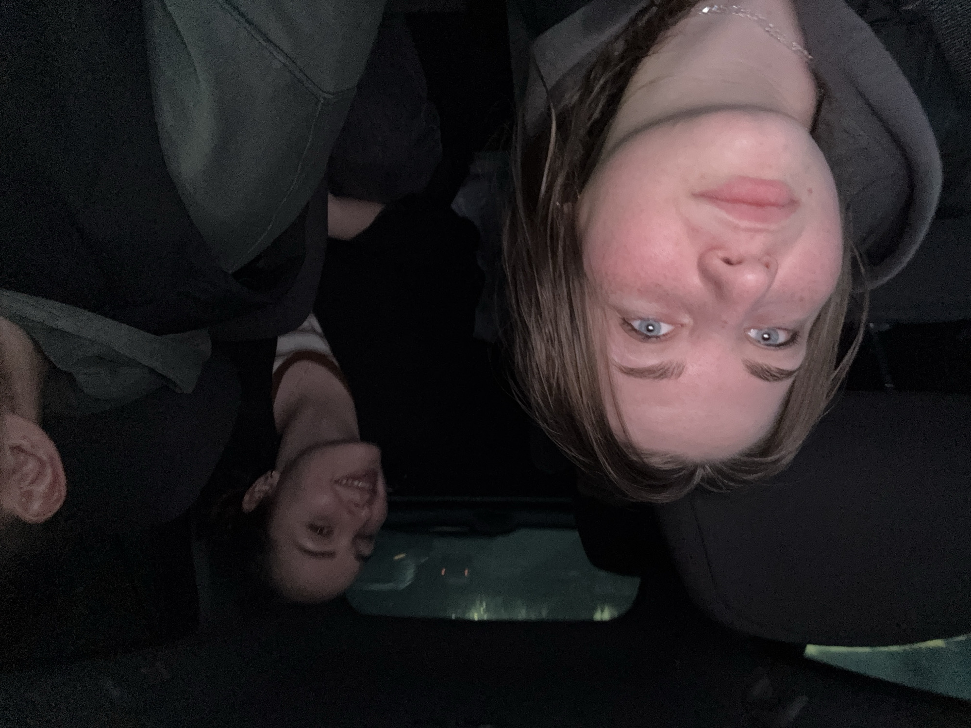 The image appears to be taken inside a car at night. Three people are visible. The interior of the car is dark, with the dashboard and windshield visible. Reflections on the windshield indicate an urban environment. The location within Chaikovsky, Russia cannot be confirmed.