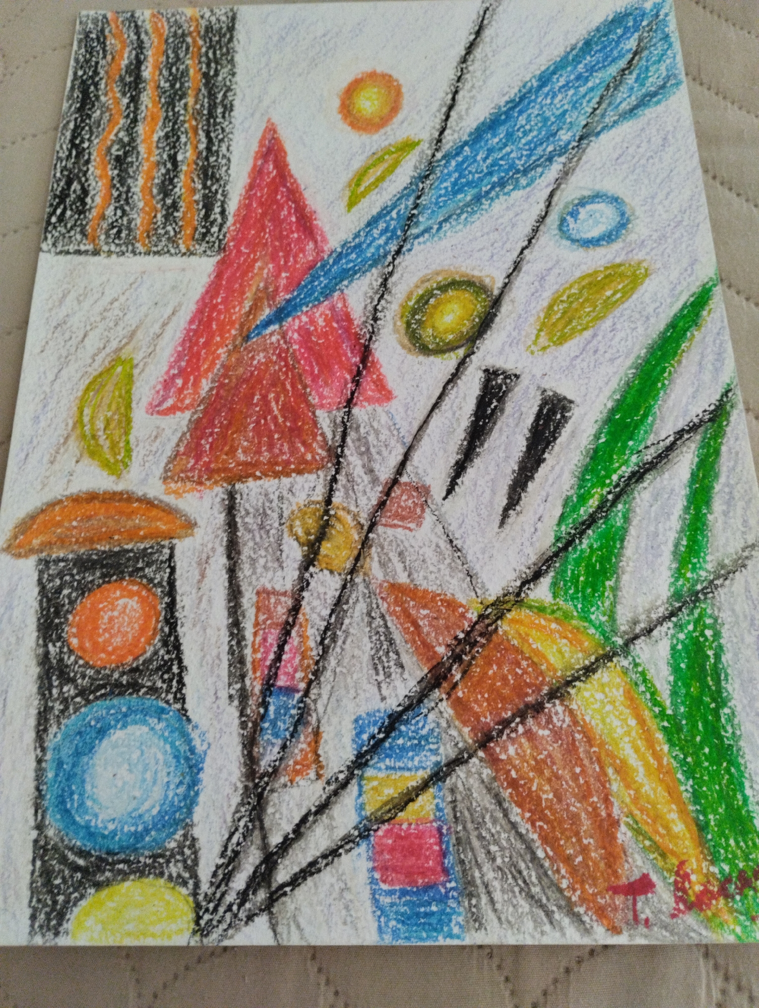 This is a colored pencil drawing on white paper featuring an abstract composition of geometric shapes and lines. The drawing is oriented vertically and appears to be laid on a textured surface, possibly a blanket. The colors used are vibrant, including red, orange, yellow, green, blue, black, and white.
Key elements of the drawing include:
* **Geometric Shapes:** There are triangles, circles, ovals, rectangles, and what appear to be stylized leaf shapes.
* **Lines:** Thin black lines are drawn diagonally across the composition, intersecting with other elements. There are also vertical black and orange lines in the upper left corner, and broad blue and green strokes that suggest movement or forms.
* **Color Application:** The colored pencils are applied with visible strokes, giving the drawing a textured and somewhat raw appearance. Some areas have layers of color, while others are more sparsely filled.
* **Composition:** The elements are arranged in a dynamic and somewhat chaotic manner, with overlapping shapes and a strong sense of depth created by the diagonal lines and layering of colors.
There are no people, discernible cityscapes, or specific locations within Mezitli, Turkey visible in this image. It is an abstract artwork.