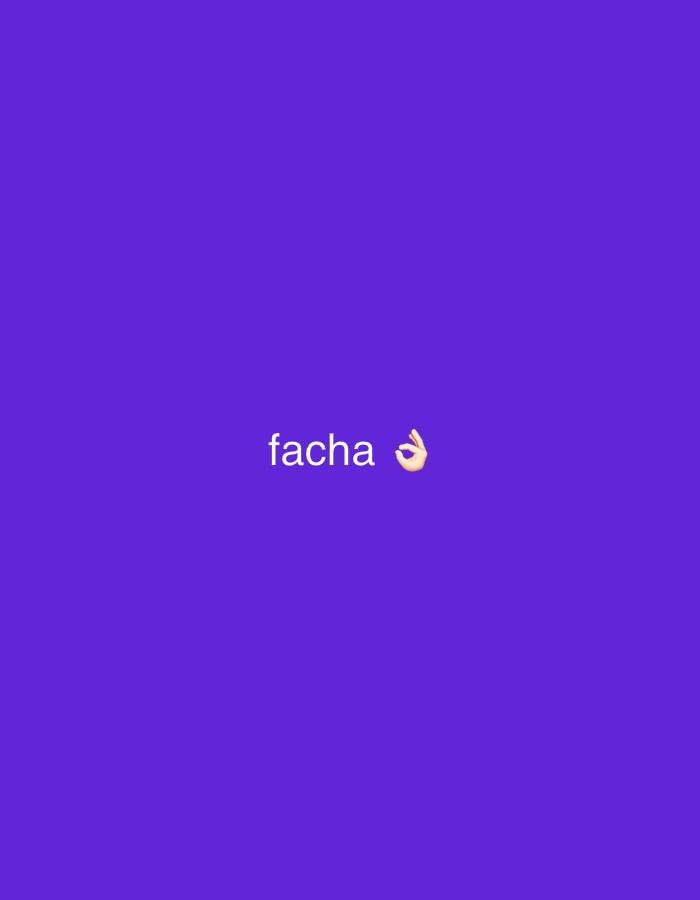 A medium shot shows the word "facha" in white sans-serif font on a purple background, accompanied by a hand emoji making an "okay" gesture. The text and emoji are centered in the frame. There is no indication of location.