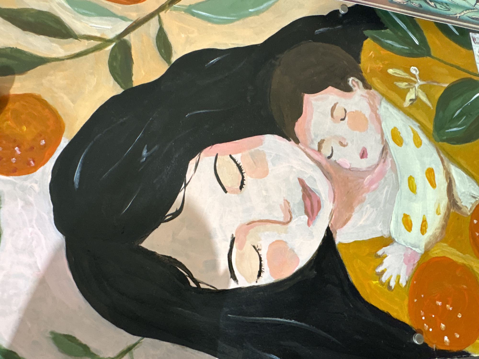 The image is a painting depicting a woman and a child sleeping. The woman has long black hair and pale skin. Her eyes are closed, and she has a serene expression on her face. The child is nestled against her, also asleep. The child has brown hair and is wearing a white shirt with yellow spots. They are surrounded by oranges and green leaves. The background is a light tan color. The painting style is somewhat impressionistic. There is no information in the image suggesting it is located in the city of Ембаево, Russia.