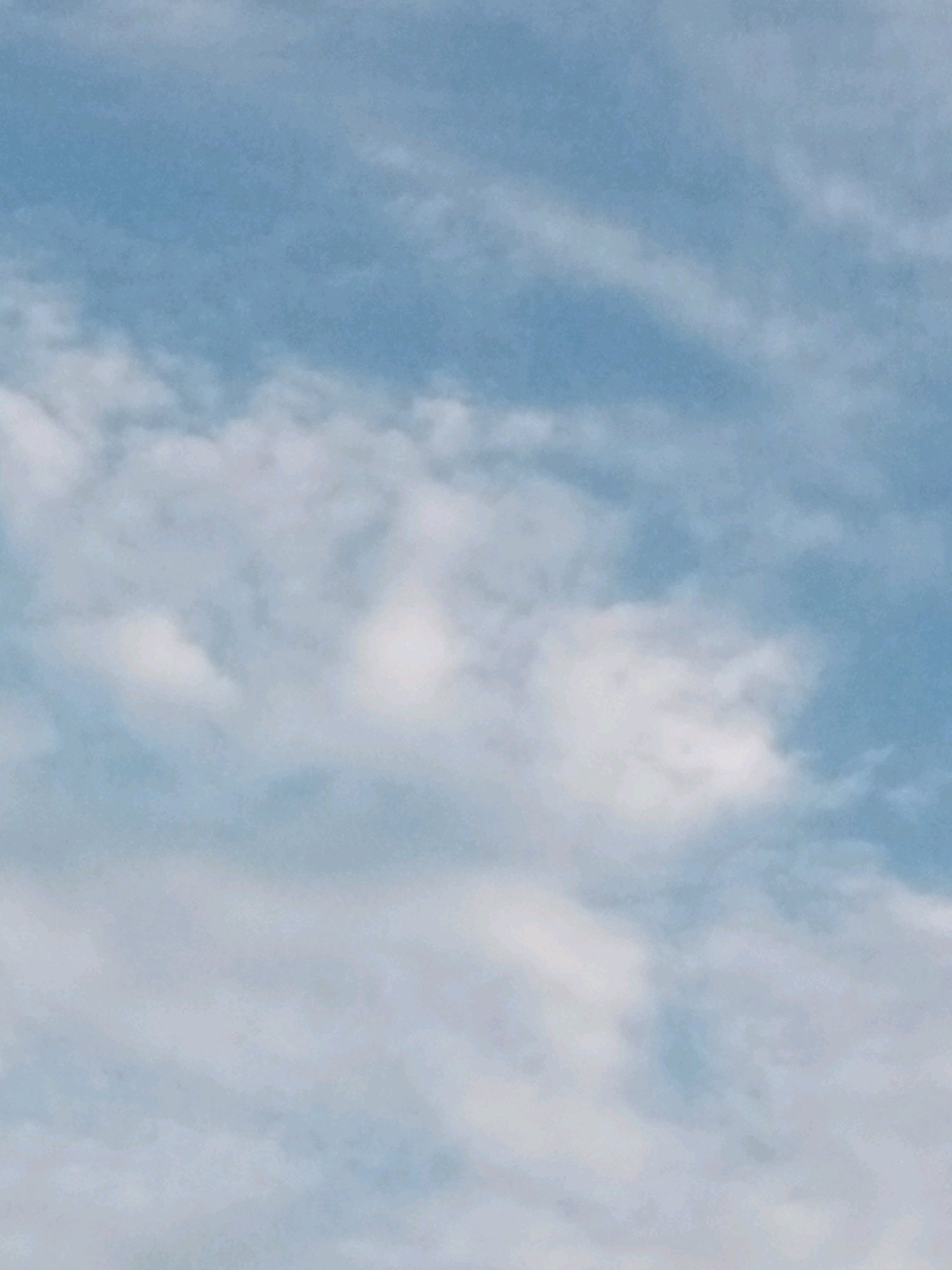 The image shows a sky with scattered clouds, a common sight in Tando Jam, Pakistan, especially during daylight hours. The sky is a light blue with wispy white clouds, some denser than others. There are no people, subjects, objects, actions, or interactions visible in this image. The environment depicted is exclusively the sky.