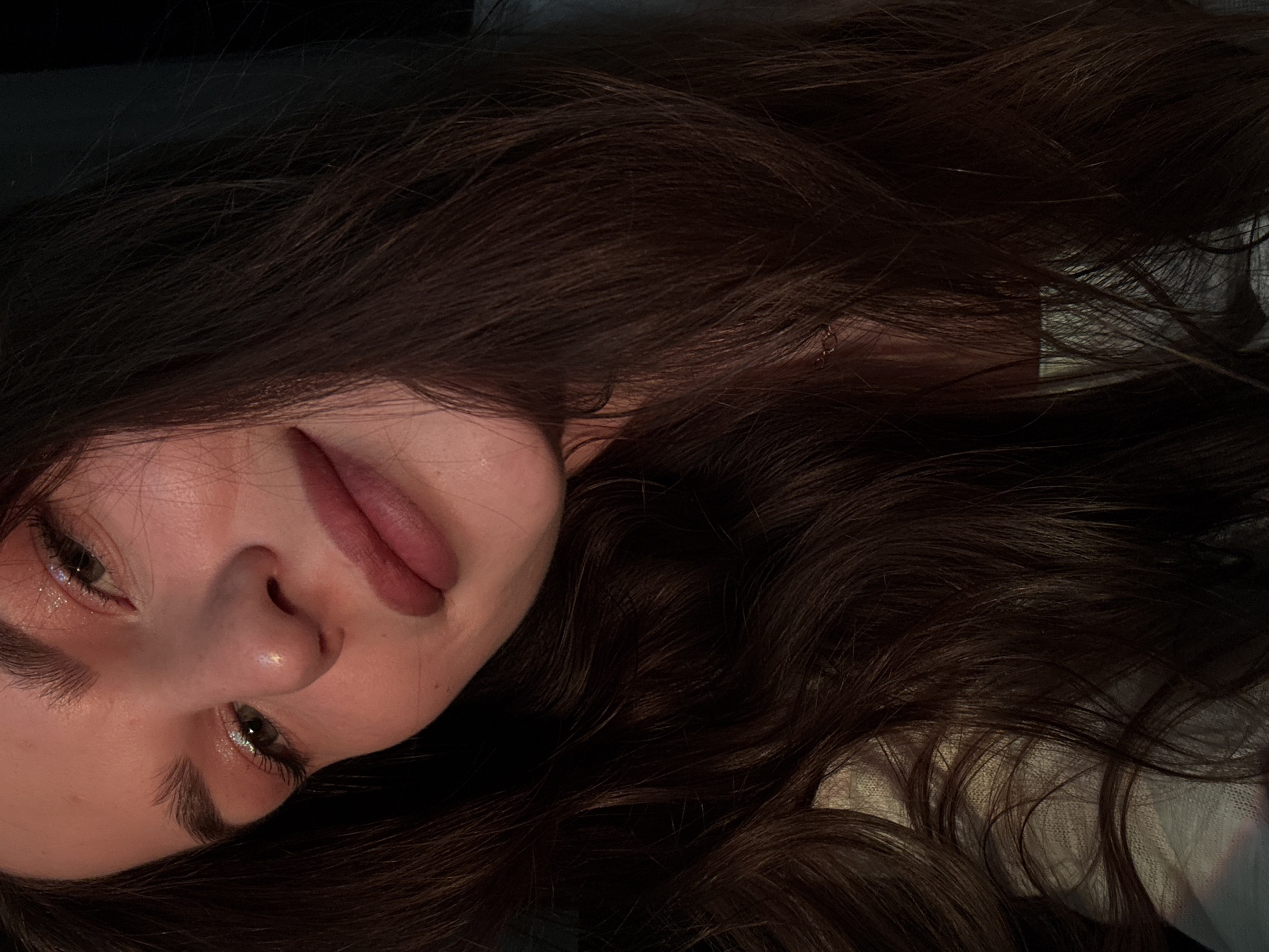 A close-up, slightly skewed perspective photograph depicts a young woman with long, dark brown hair. Her face is tilted, revealing her left eye and a portion of her right. She has fair skin, full lips, and defined eyebrows. Her eyes are adorned with a slight shimmer.
The context of the image is unclear, and there is no visible information suggesting a location in Chaikovsky, Russia.