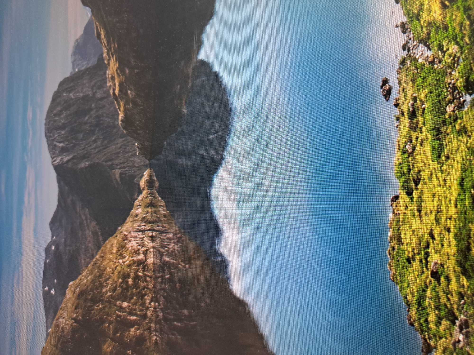 The image shows a landscape with mountains, water, and vegetation. The mountains are rocky and appear to be covered in some vegetation. The water is a light blue color. The vegetation on the right is green and moss-like. The image appears to be rotated 90 degrees clockwise. There is no indication of the location of the city of Sofia, Bulgaria.