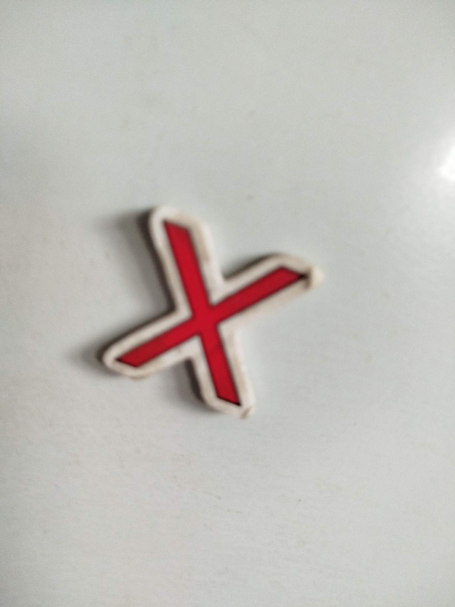 An "X" symbol, outlined in red with a white border, is the sole subject of the image. The symbol is positioned on a plain, light-colored surface, likely a wall or table. The lighting suggests an indoor environment. The specific location in Крывасельскі сельскі Савет, Belarus cannot be determined from the visual information provided.