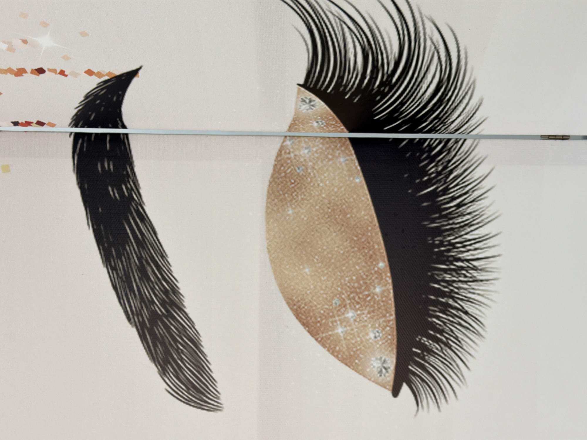 The image shows a close-up illustration of a stylized eye with heavy eyeliner and long, dramatic eyelashes. The eyelid is depicted with a shimmering golden eyeshadow adorned with small, sparkling rhinestones. Above the eye, a thick, dark eyebrow arches. The background is a plain, light color, with scattered confetti-like shapes and a subtle sparkle effect on the right side. A thin, vertical line, possibly indicating a seam or divider, runs through the center of the image, bisecting the eye. There are no people or visible actions in the image, and it is an artistic representation rather than a photograph of a real-world scene. The location of this image in Kyiv, Ukraine, cannot be determined from the visual information provided.
