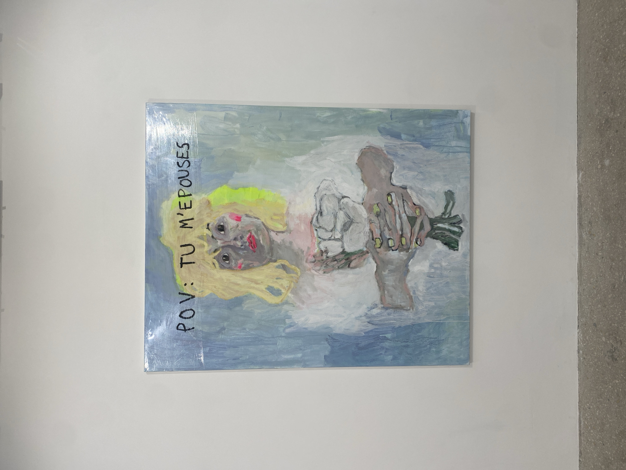 A painting hangs on a white wall. The painting depicts a woman with blonde hair and a bouquet of flowers being held out toward the viewer. The words "POV: TU M'EPOUSES" are written vertically along the left side of the painting. The environment is an art gallery or exhibition space. There is no indication that this image is in Paris, France.