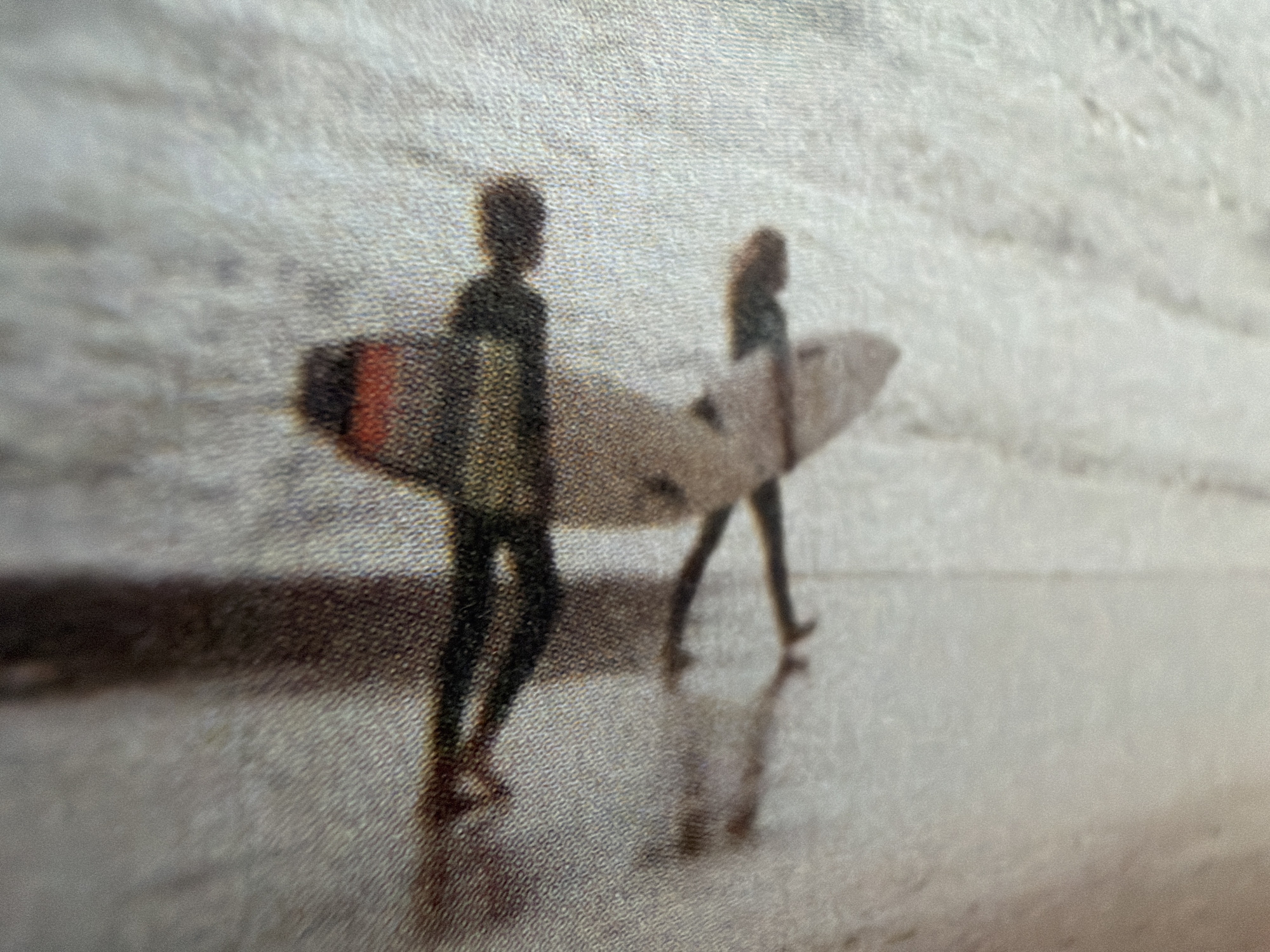 The image shows a blurred and pixelated depiction of two figures, possibly representations of people, in an abstract or textured environment that resembles fabric. The figures are elongated and stylized, with one appearing to have arms outstretched. There are areas of color, including red, black, and beige, within the figures. The background is predominantly light-colored and textured, with some darker vertical lines suggesting shadows or divisions in the material. The overall impression is of a stylized or artistic representation rather than a realistic photograph. There is no identifiable location in the city of Kyiv, Ukraine.