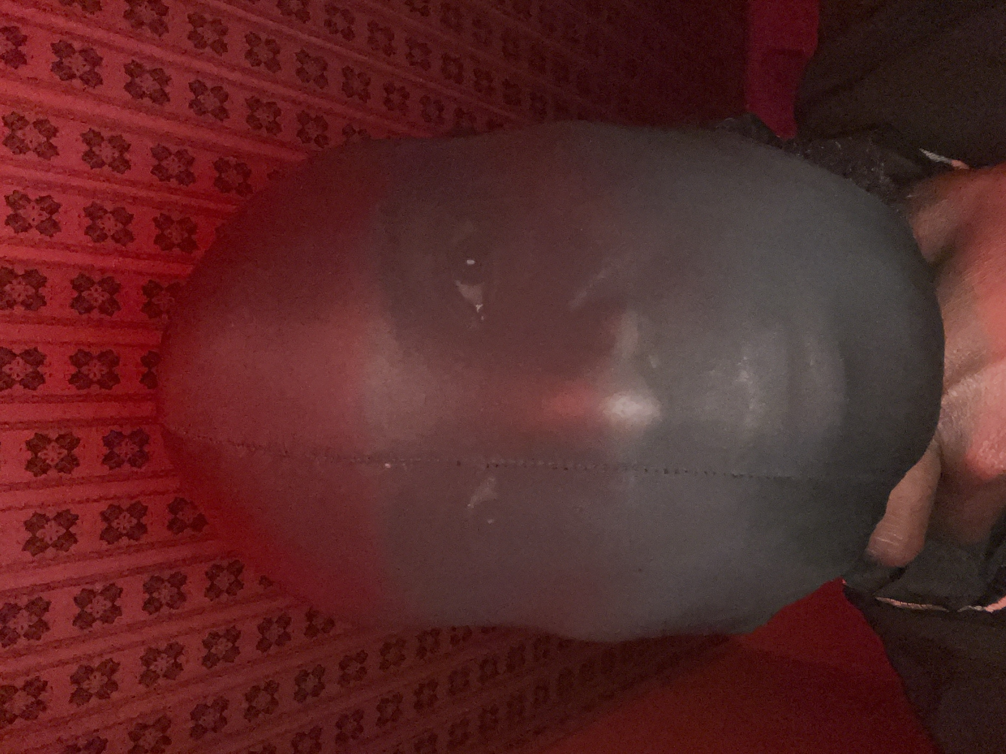 A gray, spherical object rests on a red patterned surface. A hand is visible on the right side of the sphere. The location is unknown; there is no indication of Gura Top, Nigeria.