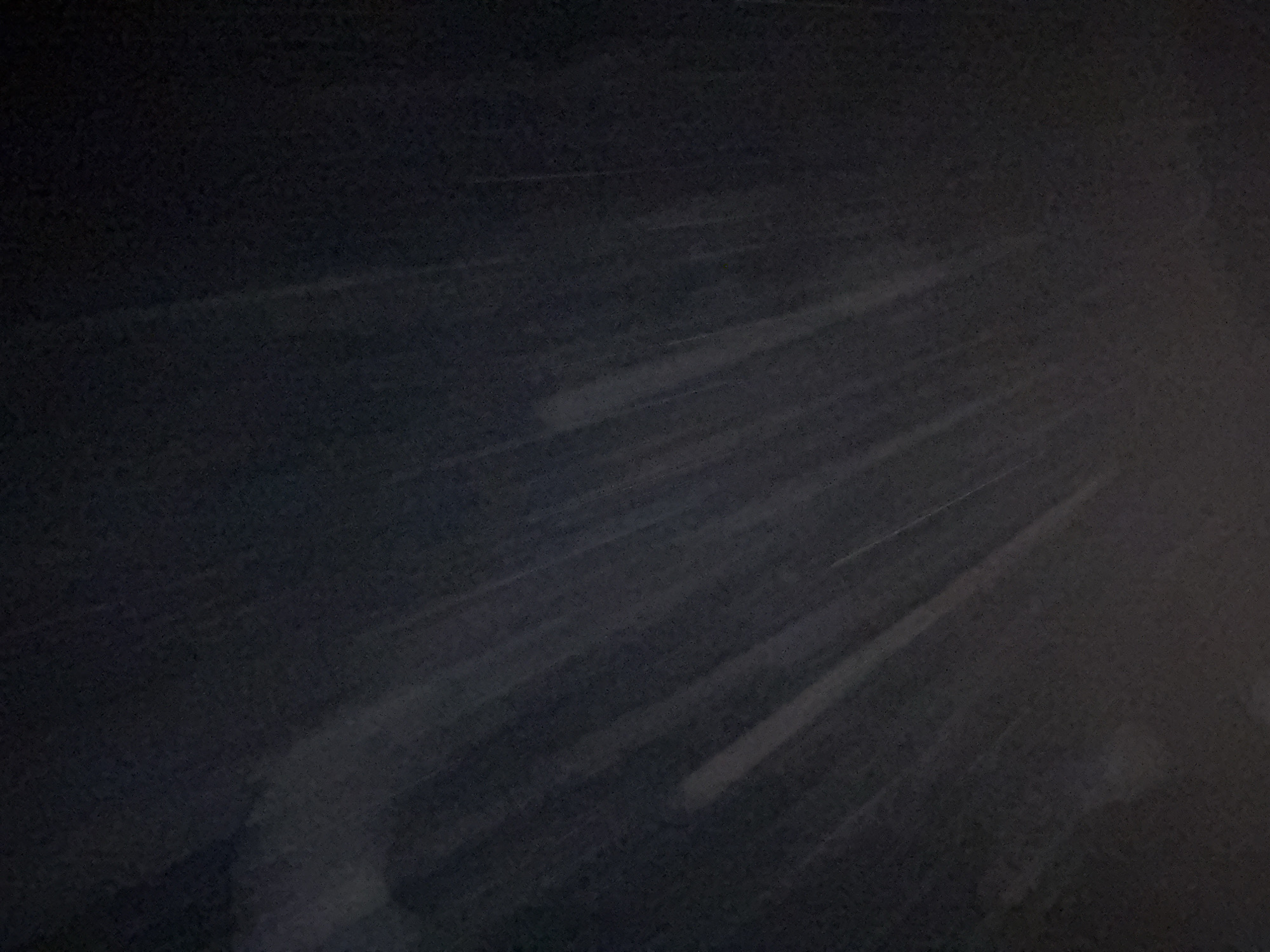 This image depicts a dark, abstract scene with faint diagonal lines of light appearing to streak across a textured, dark background. The lines are concentrated in the center and right portions of the image, fanning outwards. The overall impression is one of movement or a pattern on a surface. There are no discernable people, objects, or specific environmental features that would allow for identification of a location within the city of Industriya, Russia, or any other specific place. The image is too abstract and lacking in detail to provide any further forensic or matter-of-fact description.