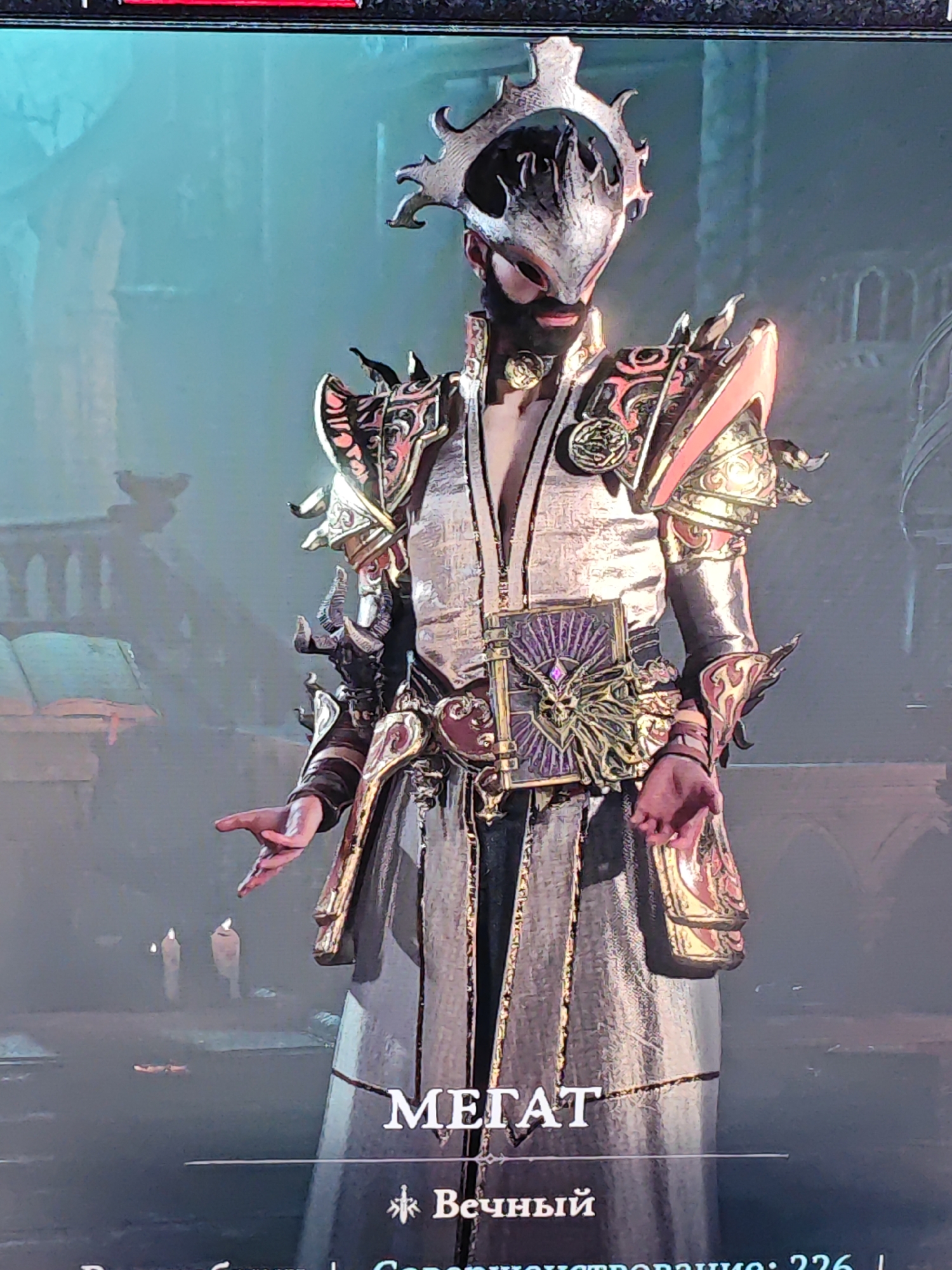 The image shows a full-body, medium shot of a character in ornate, fantasy-style armor. The character is wearing a silver and gold helmet with intricate, flame-like protrusions. The armor is detailed with red and gold accents, shoulder pauldrons, bracers, and a decorative belt featuring a skull motif. The character is dressed in a long, flowing robe or skirt. The background is dimly lit and appears to be an interior space with architectural elements suggestive of a gothic or medieval setting, including what looks like a lectern with an open book on the left and arched doorways or windows in the background. Two candles are visible on a surface in the lower left portion of the image. Text overlays at the bottom of the image are in a Cyrillic script, with "МЕГАТ" prominently displayed. The presence of this text and the visual style suggest the image is from a video game or similar digital media. There is no identifiable information within the image to connect it to the city of Zhlobin, Belarus.
