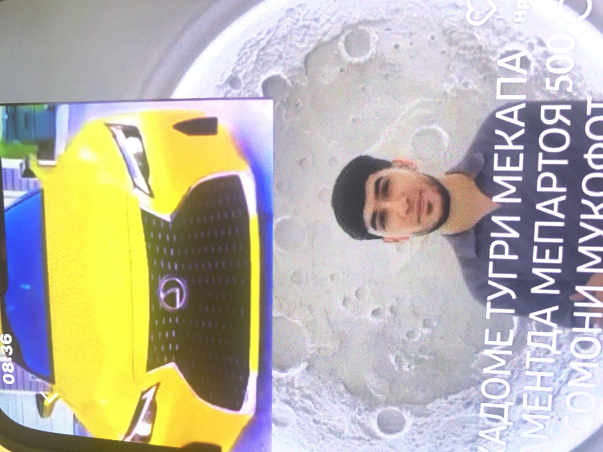 The image displays a split scene. The top portion features the front of a bright yellow Lexus car. The bottom portion shows a young man with dark hair and a beard, wearing a dark collared shirt, standing in front of a superimposed image of the moon's surface. White text is overlaid on the moon image, with partial lines visible. The car appears to be on a street, possibly in a residential or commercial area, indicated by the blurred background that suggests buildings. The overall quality of the image is low, with visible pixelation and graininess, suggesting it was taken with a low-resolution camera or has been compressed. The location in Bassetlaw, United Kingdom, cannot be determined from the visual information provided in the image.
