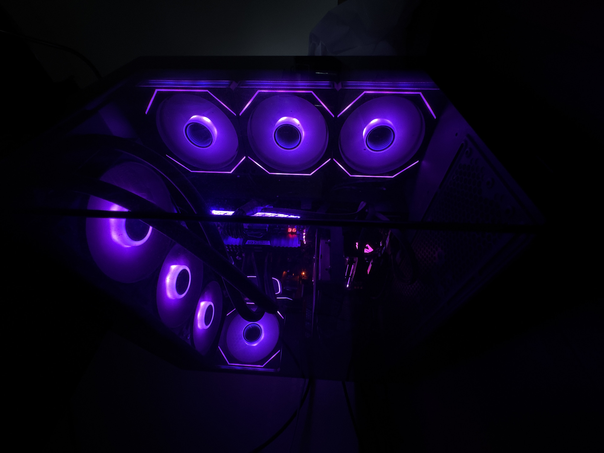 The image shows a computer case with multiple purple LED fans illuminating the interior. The computer is in a dark environment, with only the glow from the fans providing light. There are no people visible in the image, and no specific details about the location in Velingrad, Bulgaria are discernible. The computer appears to be stationary and not in use.