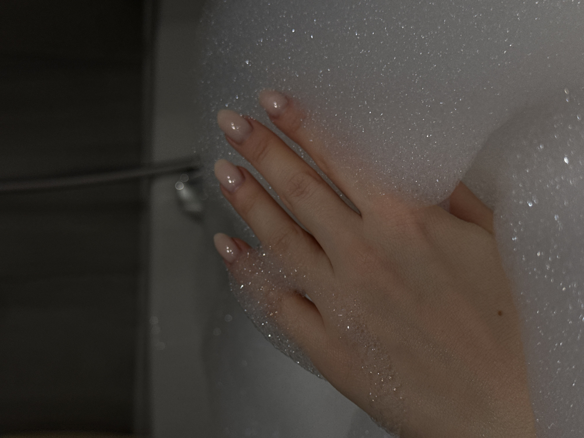 A hand rests in a bath filled with white foam. The hand has pale skin and light pink fingernails. The background shows a metallic faucet and a tiled wall, likely within a bathroom setting. Location information indicates Khimki, Russia, but the image content does not provide supporting evidence of this location.