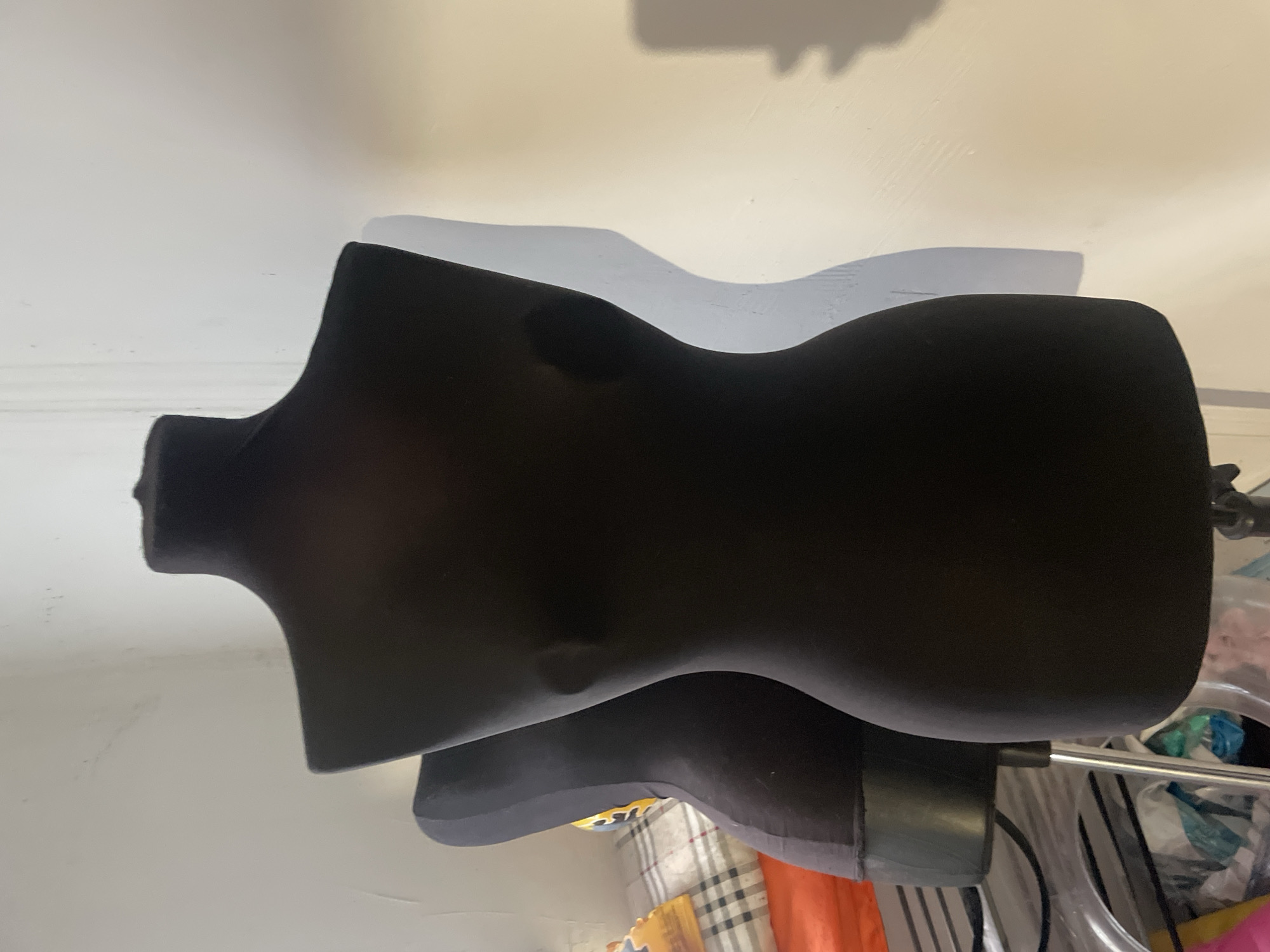 A black mannequin torso is visible in an indoor environment. The background appears to be a wall. No information is available to suggest this image was taken in Olginka, Russia, nor are there any people present in the image.