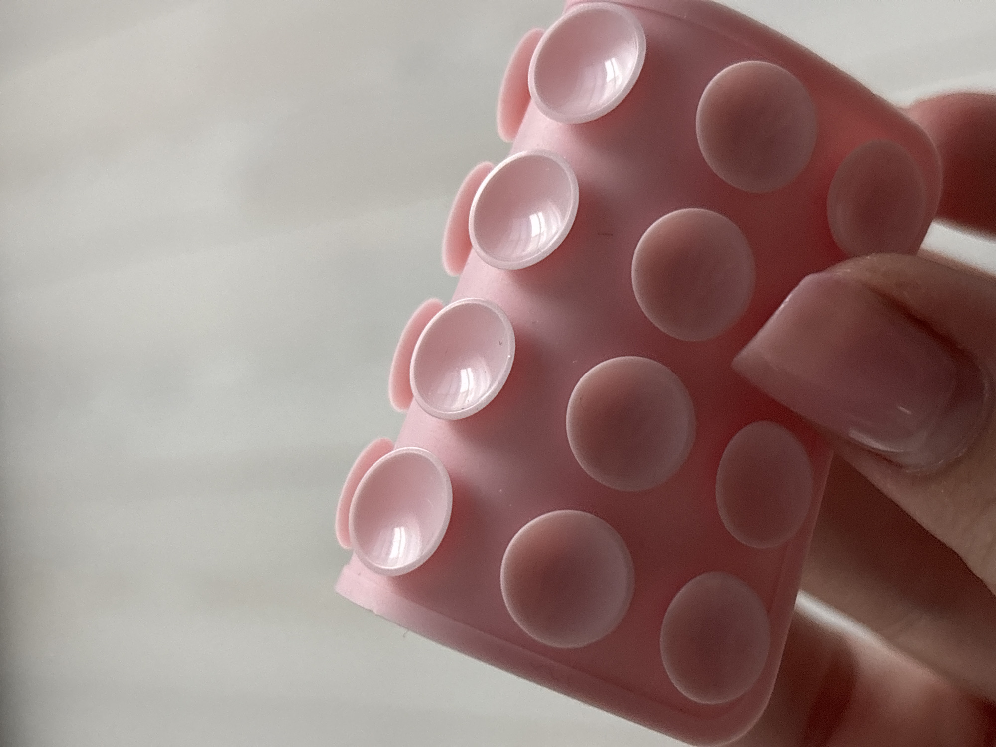 A close-up image features a cylindrical pink object covered in suction cups, held by a human hand with long, light pink fingernails. The background is a blurred off-white. The object appears to be made of a soft material like silicone or rubber. The location in Chaikovsky, Russia, is not identifiable from the image.