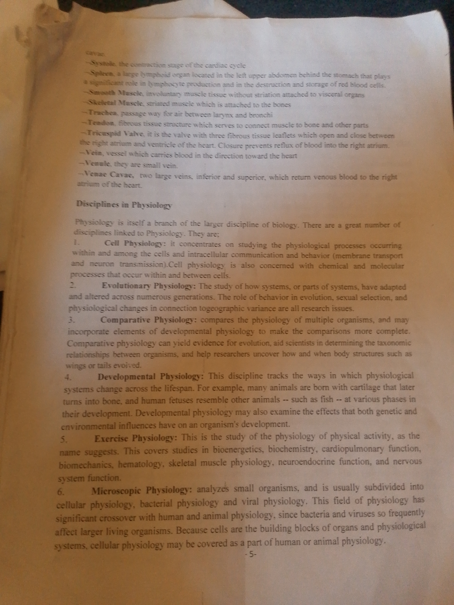 This media file is a photograph of a page from a textbook or academic document. The subject matter is scientific, specifically related to physiology and biology. The page contains definitions of various physiological terms and outlines different disciplines within the field of physiology, such as Cell Physiology, Evolutionary Physiology, Comparative Physiology, Developmental Physiology, Exercise Physiology, and Microscopic Physiology.
The document appears to be printed on white paper. The text is in black ink. There are no images or illustrations present, only text. The layout includes bulleted lists and numbered points, typical of an educational text.
Visible text includes:
- Definitions of biological terms like "Systole," "Spleen," "Smooth Muscle," "Skeletal Muscle," "Trachea," "Tendon," "Tricuspid Valve," "Vein," "Venule," and "Venae Cavae."
- A heading: "Disciplines in Physiology."
- Descriptions of various branches of physiology, numbered 1 through 6.
- A page number "-5-" at the bottom right corner of the page.
There are no people, animals, or specific scenes depicted. The setting is implied to be an academic environment where such a text would be studied. No time of day, weather, or location cues beyond the academic context are present. The overall tone of the document is informative and educational. There are some minor blemishes and shadows on the page, suggesting it's a photograph of a physical document. The location context of Jalingo, Nigeria, is not evident from the image itself but is provided as external information.
