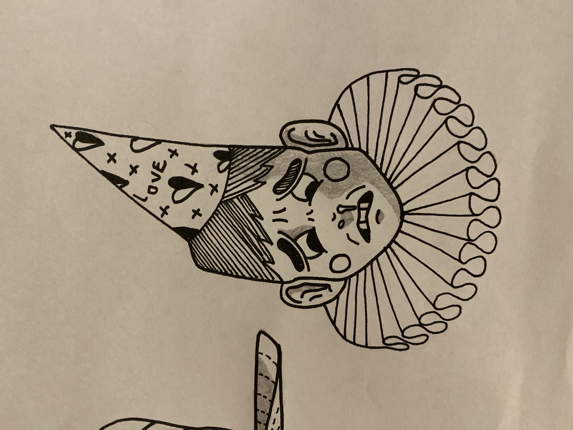 The image is a black and white sketch of a clown. The clown is wearing a cone-shaped hat with hearts, x marks, and the word "LOVE" on it. The hat has vertical stripes at the base. The clown has large eyes, a round nose, round cheeks, and a ruff around its neck. The background is a plain, light-colored surface. There is a partial view of the clown's costume. There is no evidence to suggest that it is located in Ushuaia, Argentina.