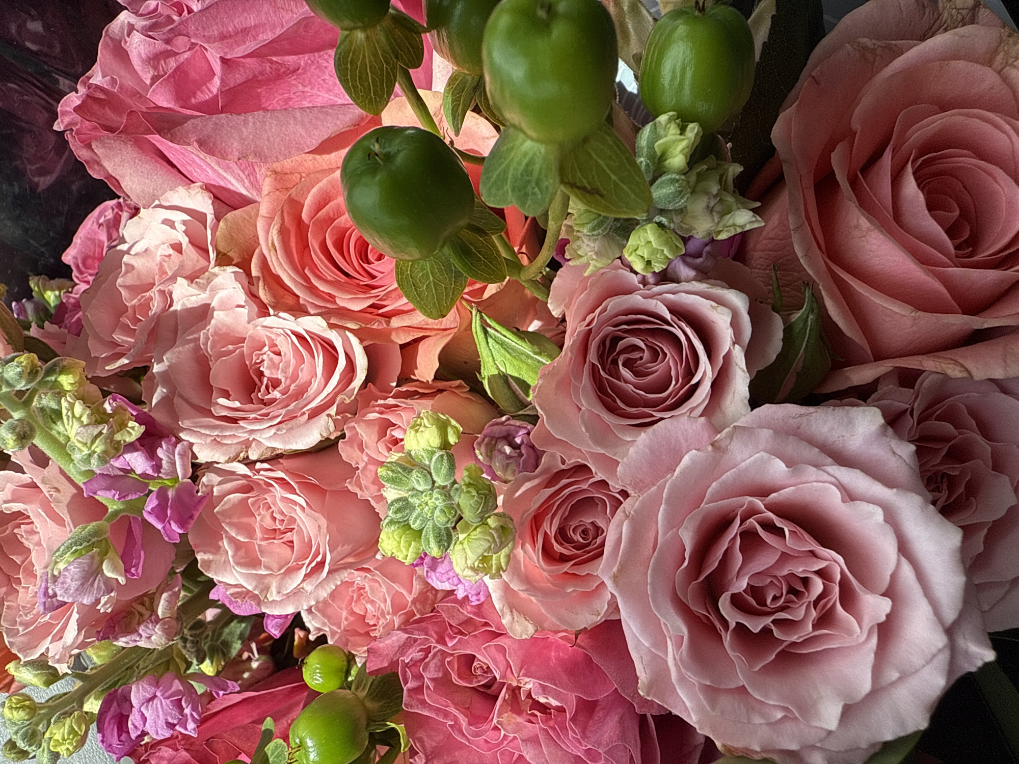 This is a close-up image of a bouquet of flowers, mainly roses, with varying shades of pink. There are also some green berries interspersed among the roses.
The location is the city of Sunrise, United States of America.