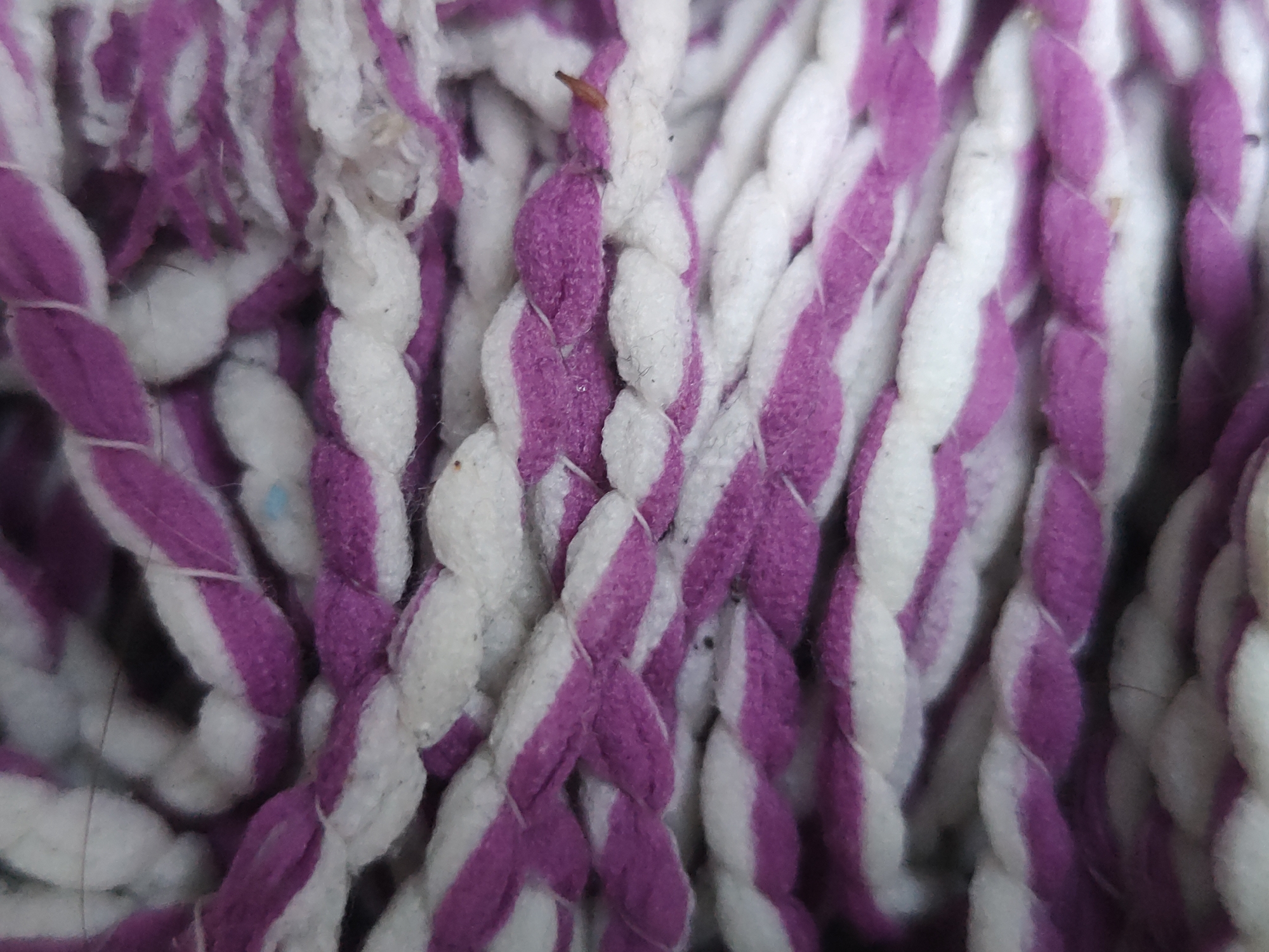 Close-up of a braided purple and white mop head. The image shows the texture and pattern of the mop strands in detail. Location: Unknown, Unknown. No people are visible.