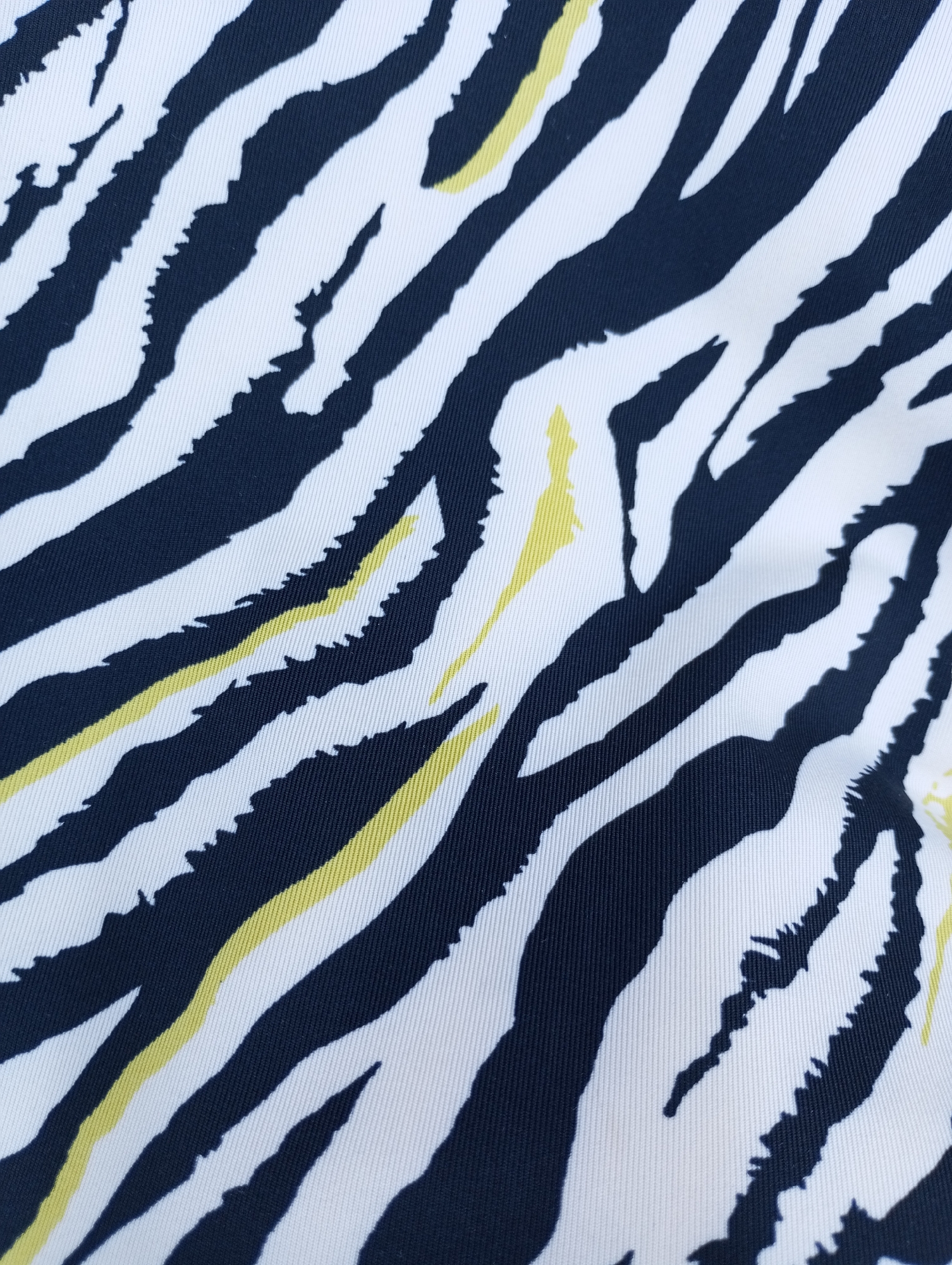 The image shows a close-up of a fabric with a zebra-like pattern. The stripes are primarily navy blue and white, with sporadic yellow streaks interspersed. The fabric has a visible weave, indicating a textile material. There are no people, specific objects, or indications of the city of Izhevsk, Russia in the image.